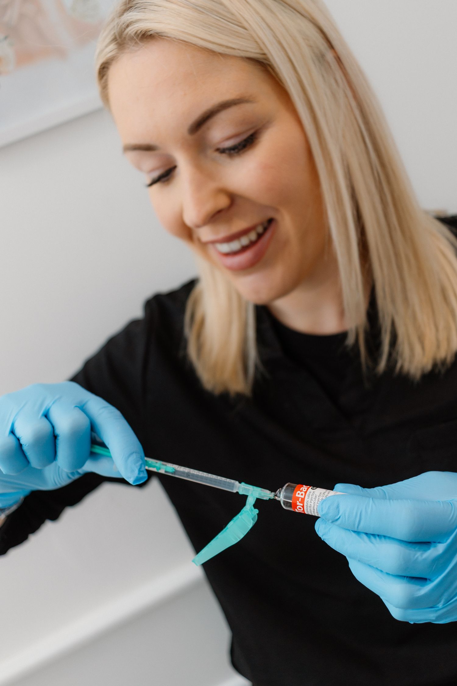 Close-up of hands in blue medical gloves preparing an injection.