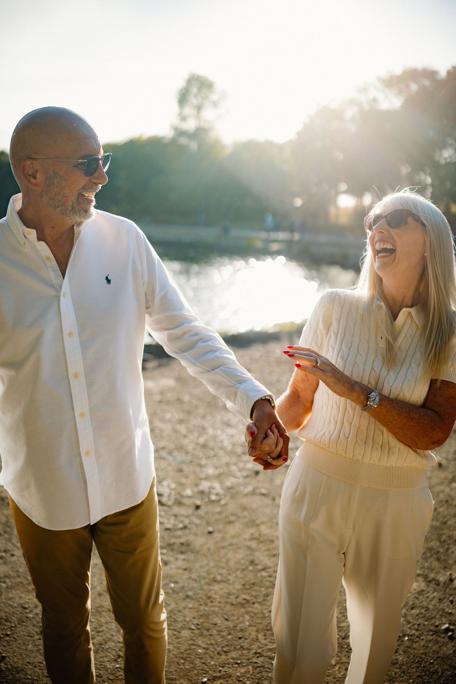 Happy couple laughing together during a sunset photoshoot by the water.