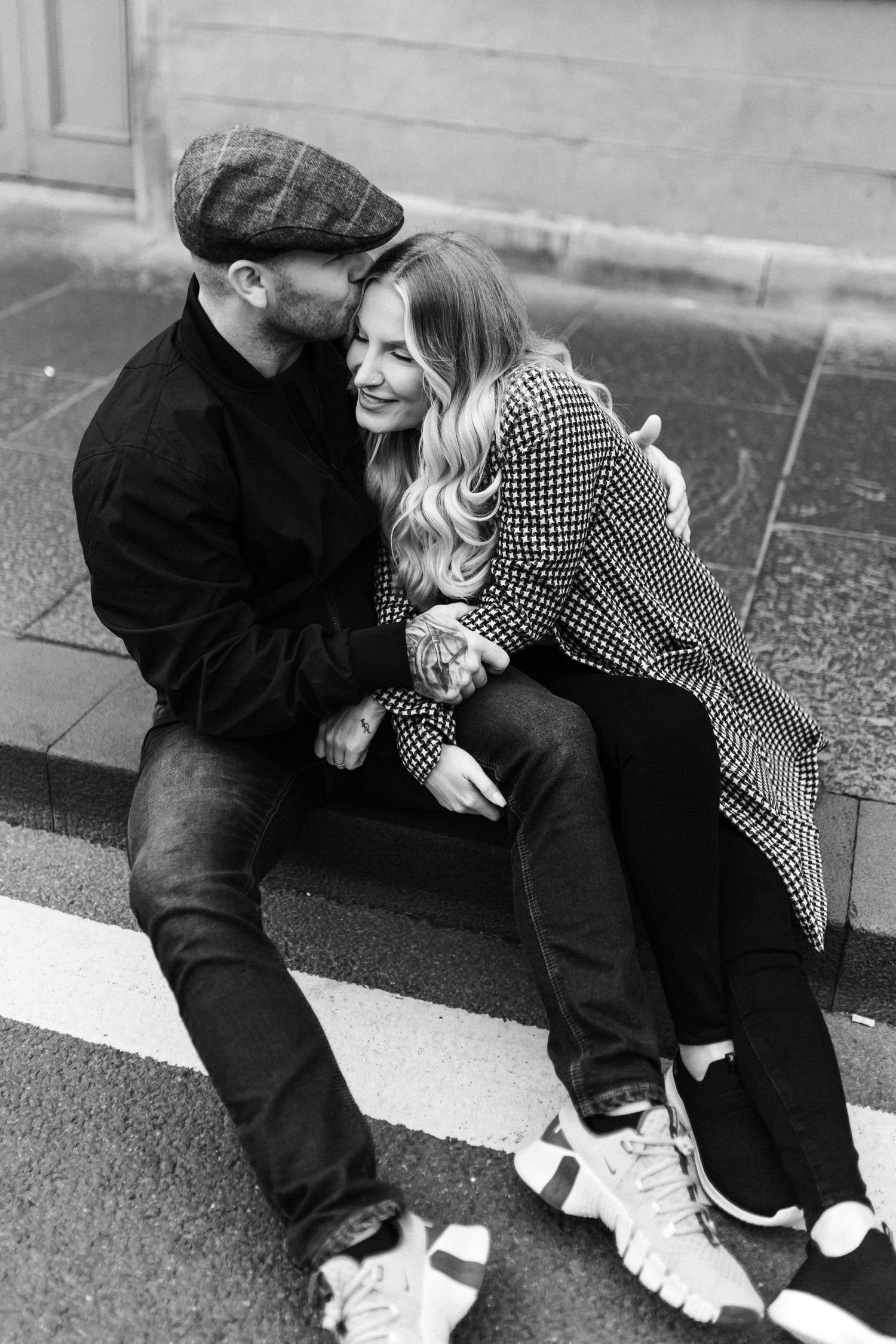 Couple sharing intimate moment while sitting on urban curb.