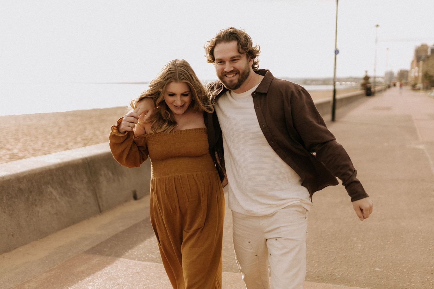 Couple strolling together on a seaside walkway in warm autumn tones.