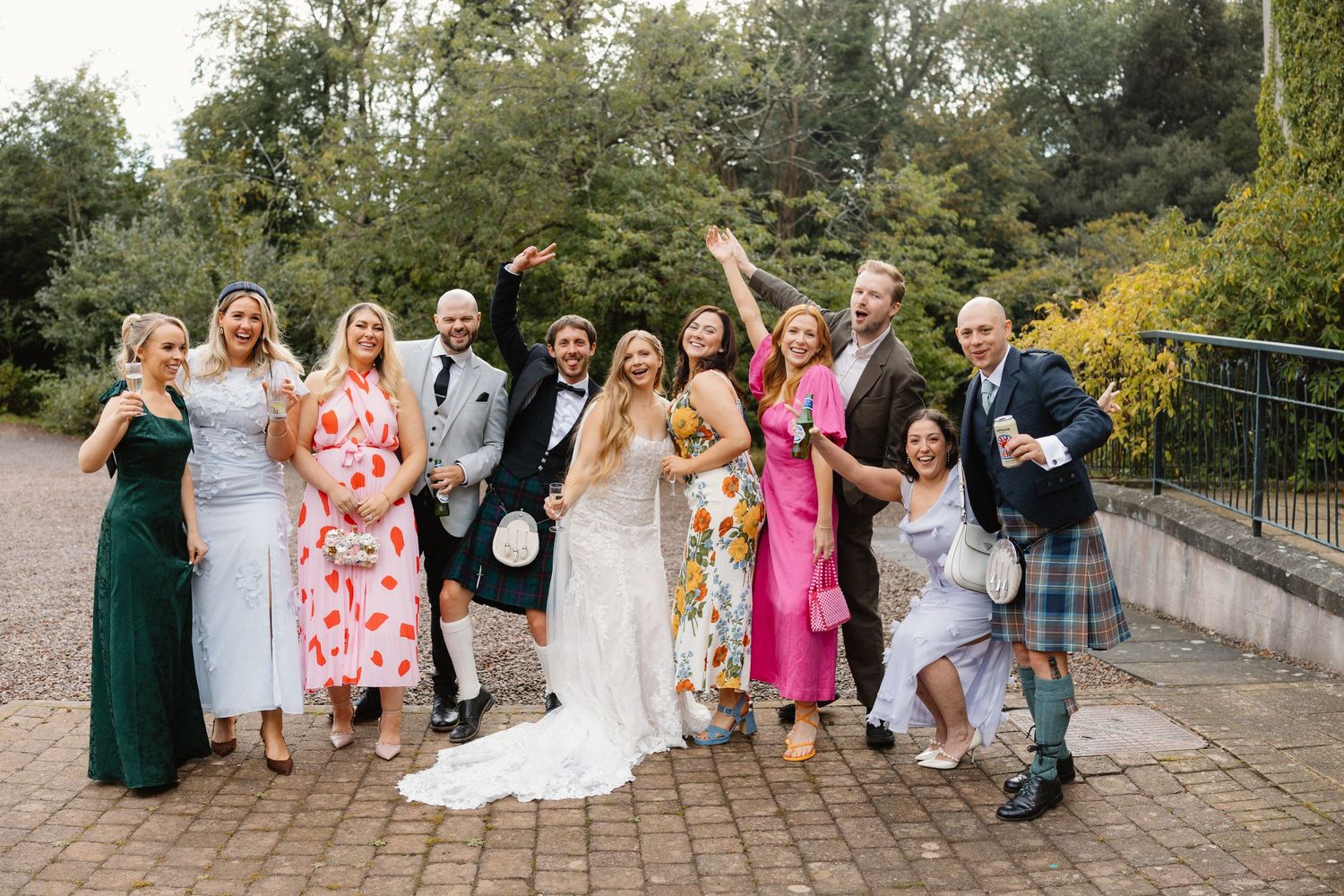 Wedding party gathered outdoors for group photos on stone steps.