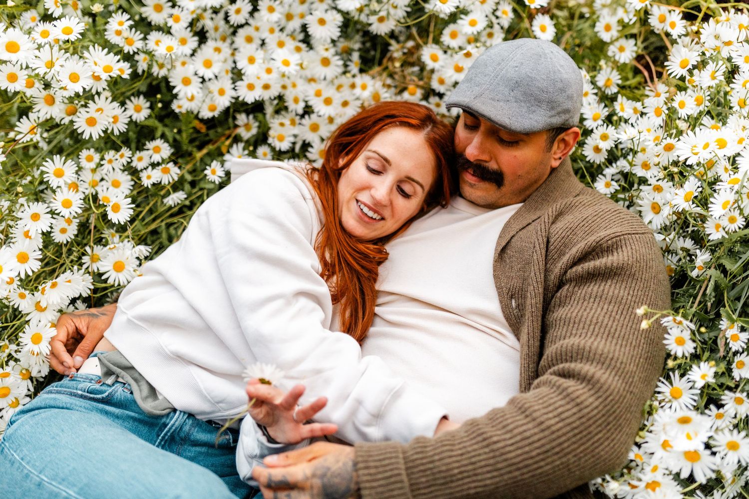 Intimate sequence among blooming daisies showing couple in casual attire.