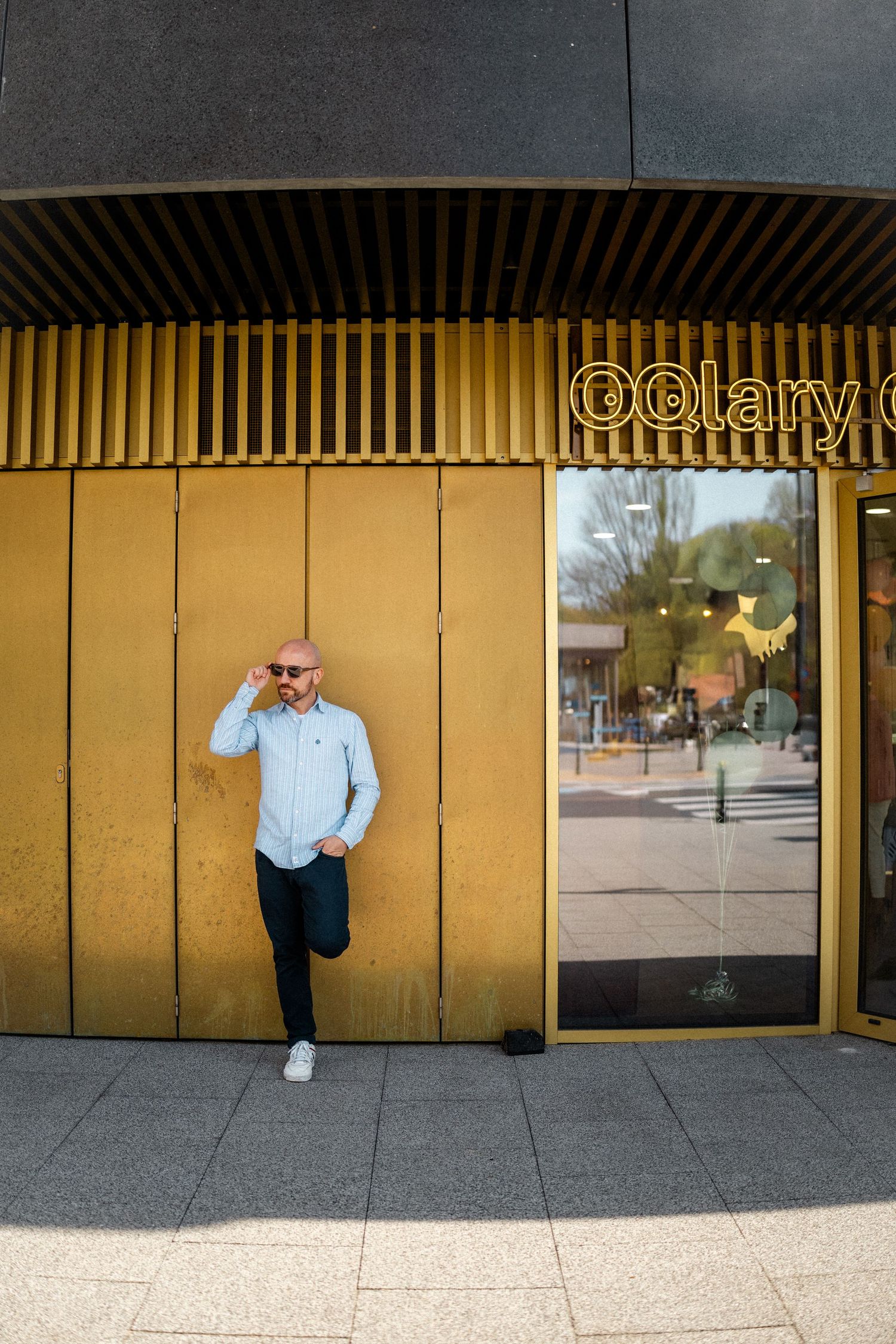 Gold metallic wall panels creating geometric pattern on urban storefront.