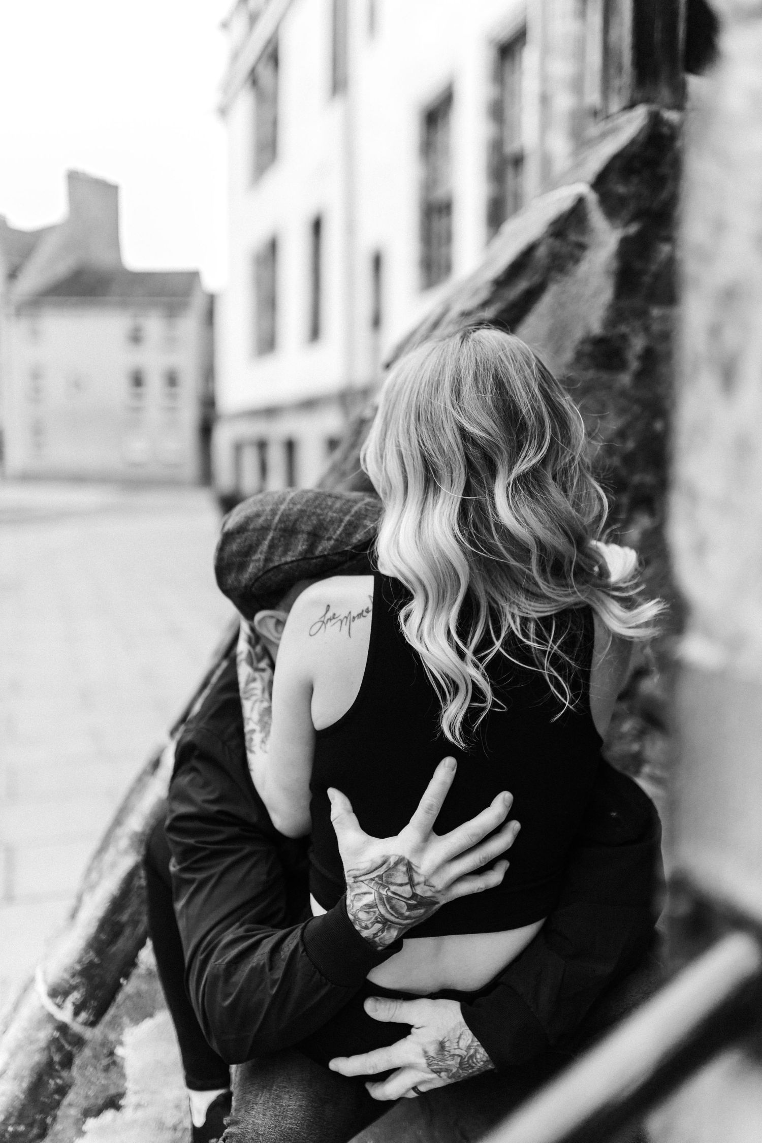 Black and white photographs of couple sharing tender embraces against urban backdrop.