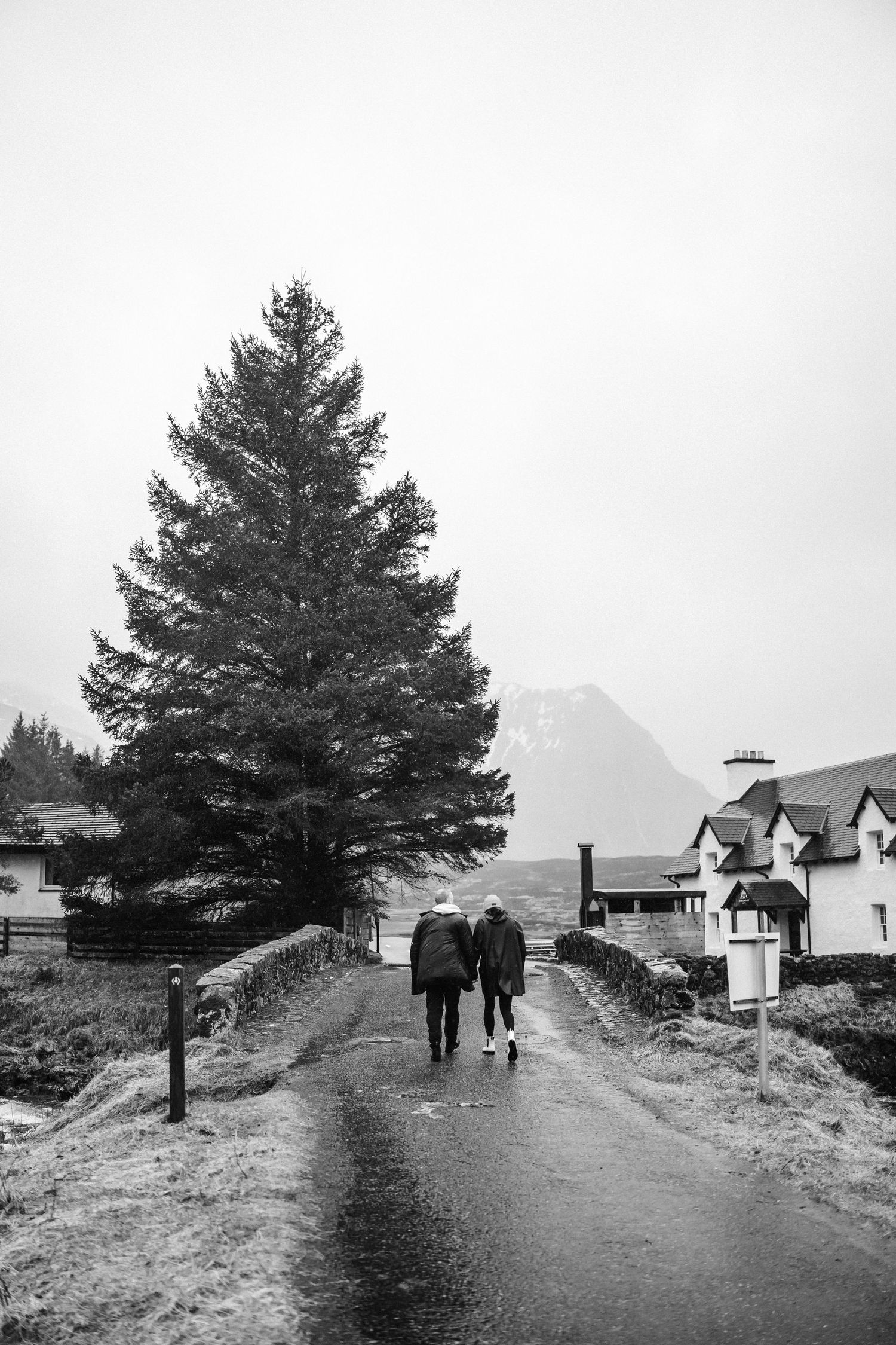 Two people walking on a path through the Scottish countryside with houses in the background.
