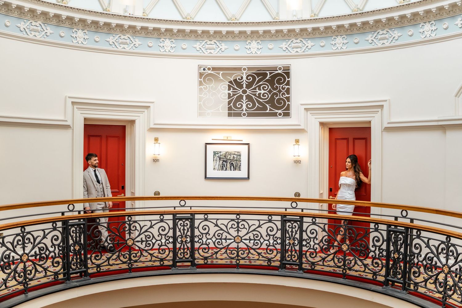 Ornate curved balcony railing with decorative metalwork in a classical building interior.