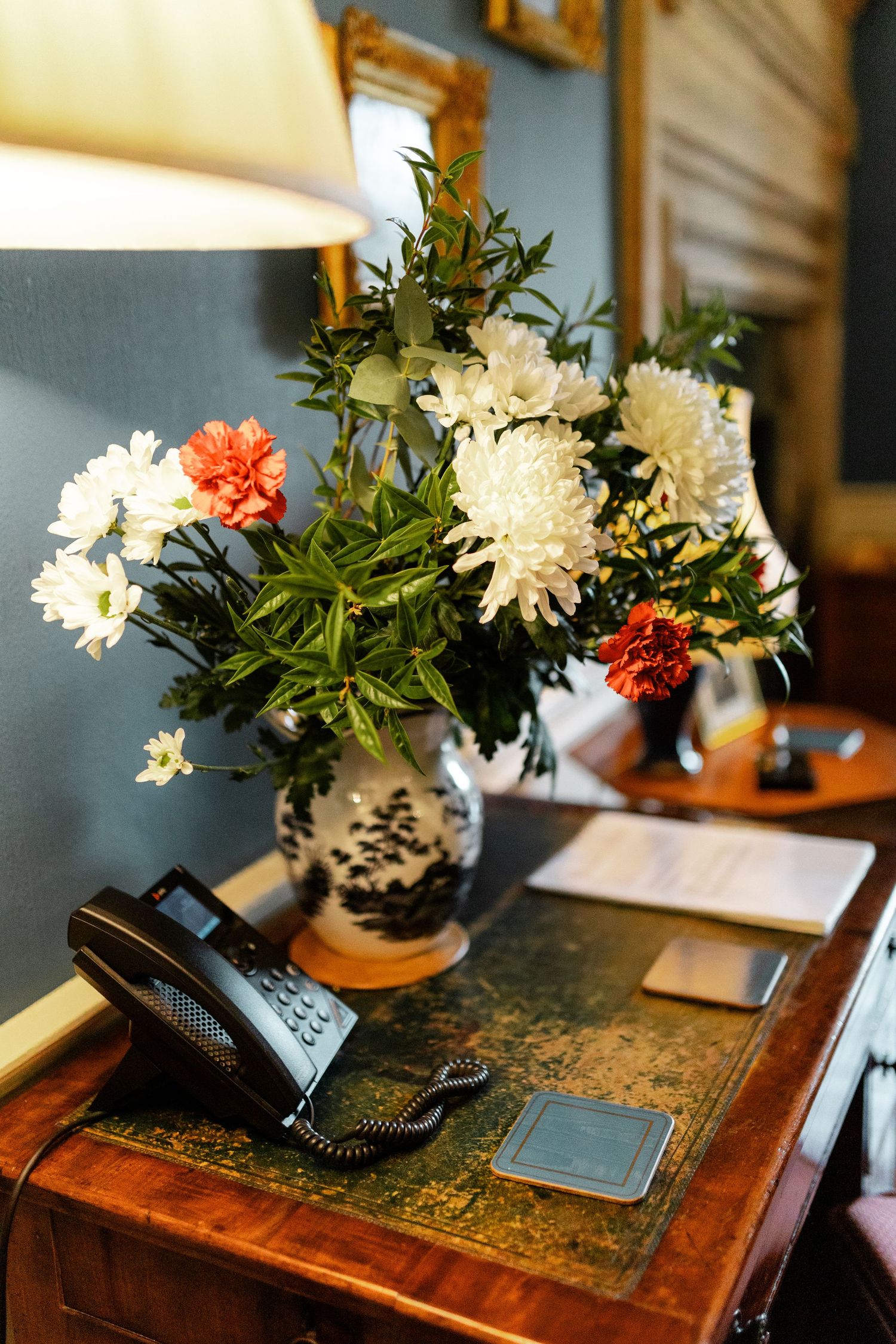Elegant floral arrangements with white and orange flowers displayed on an antique wooden table.
