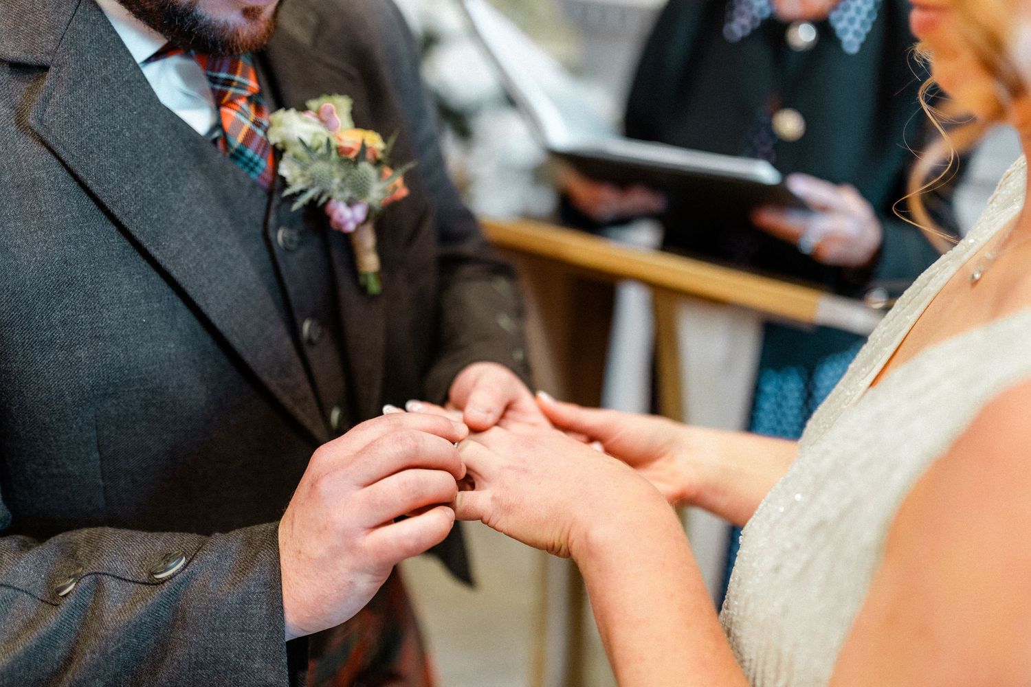 Close-up of a bride placing a wedding ring on the groom's finger during the ceremony.