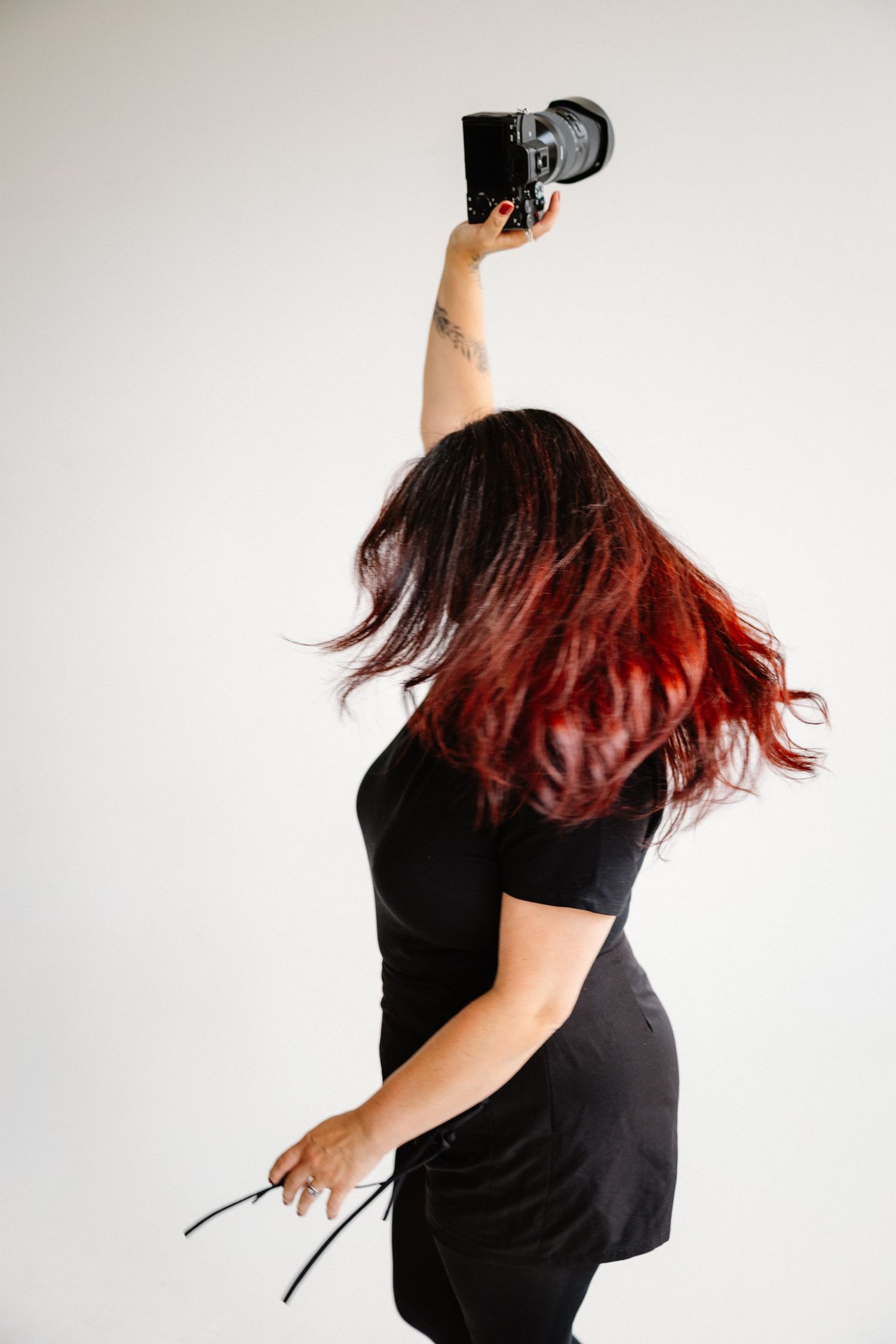 Dynamic shot of person with red-tinted hair holding camera overhead in motion.