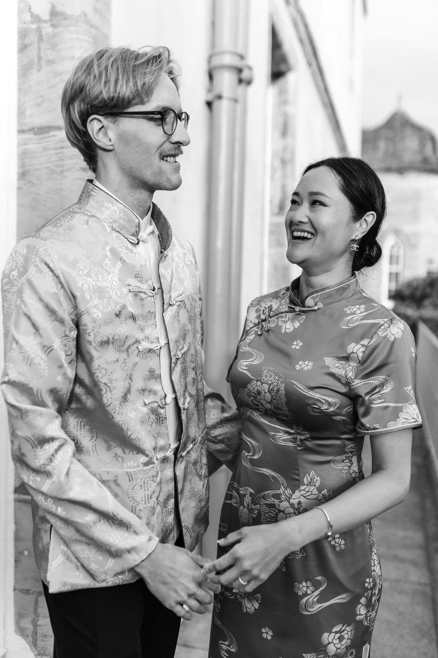 Black and white portrait of couple in traditional Chinese and Western formal wear.