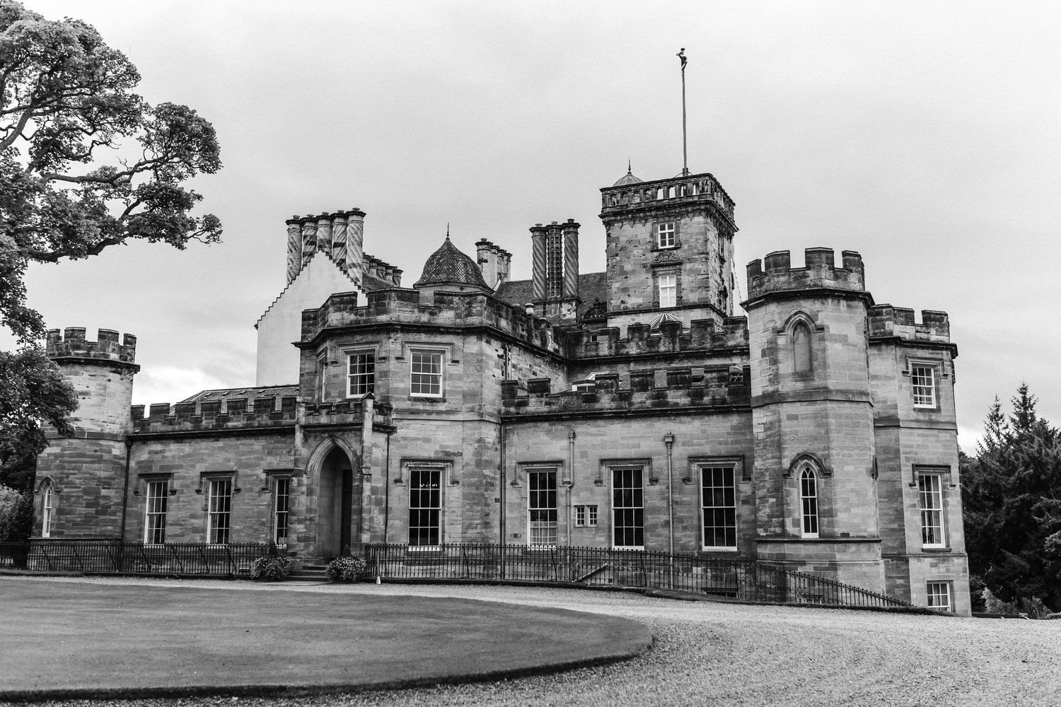 Historic stone castle building with multiple wings and turrets shown from different exterior angles in black and white.