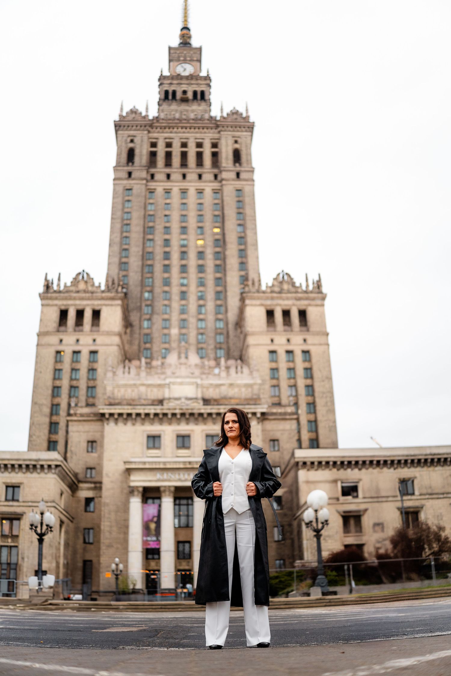 Architectural fashion shoot featuring historic Palace of Culture building in dramatic urban setting.