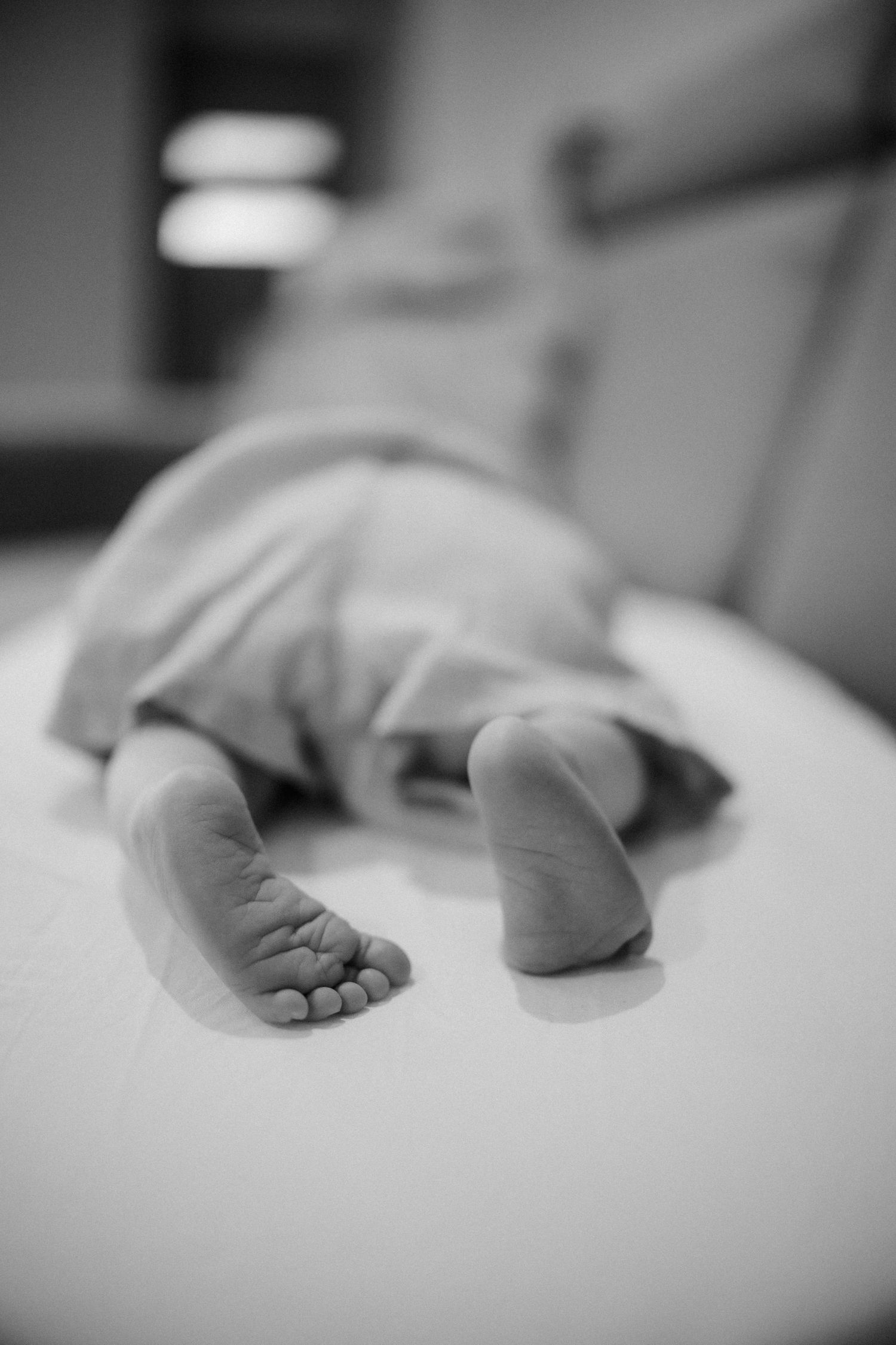 Artistic black and white close-up of tiny baby feet on white fabric.