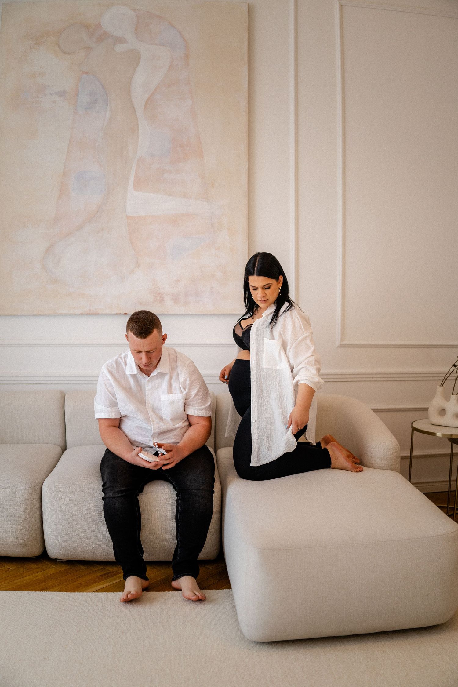 Minimalist indoor photoshoot with people sitting on modern white furniture.