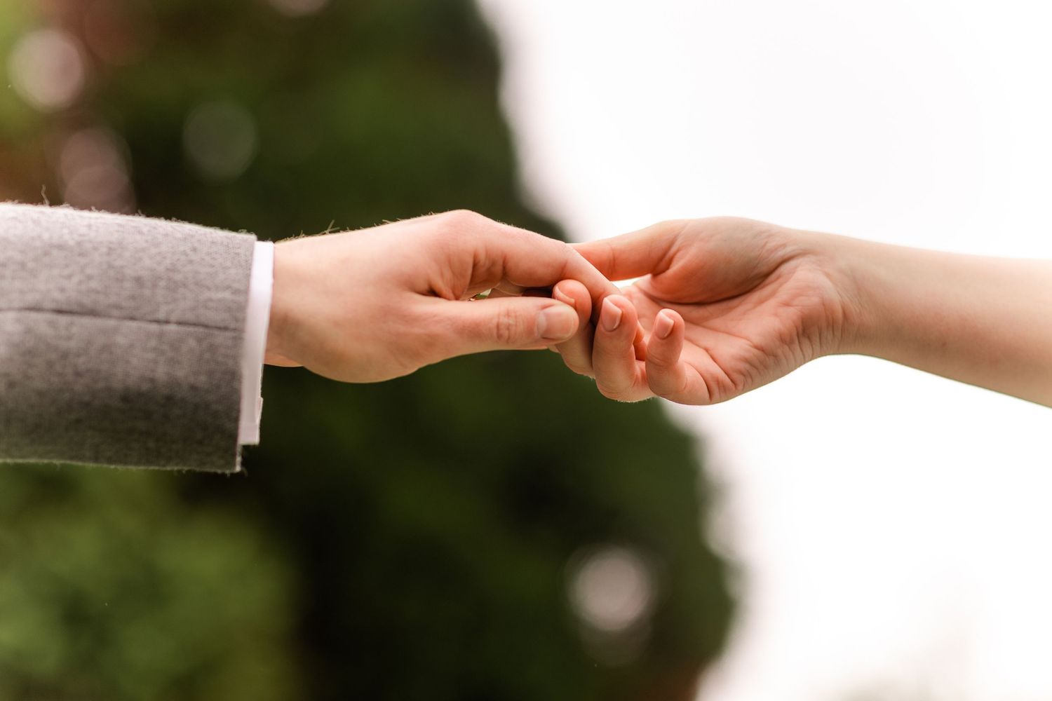 Close-up of hands reaching towards each other against a blurred background.