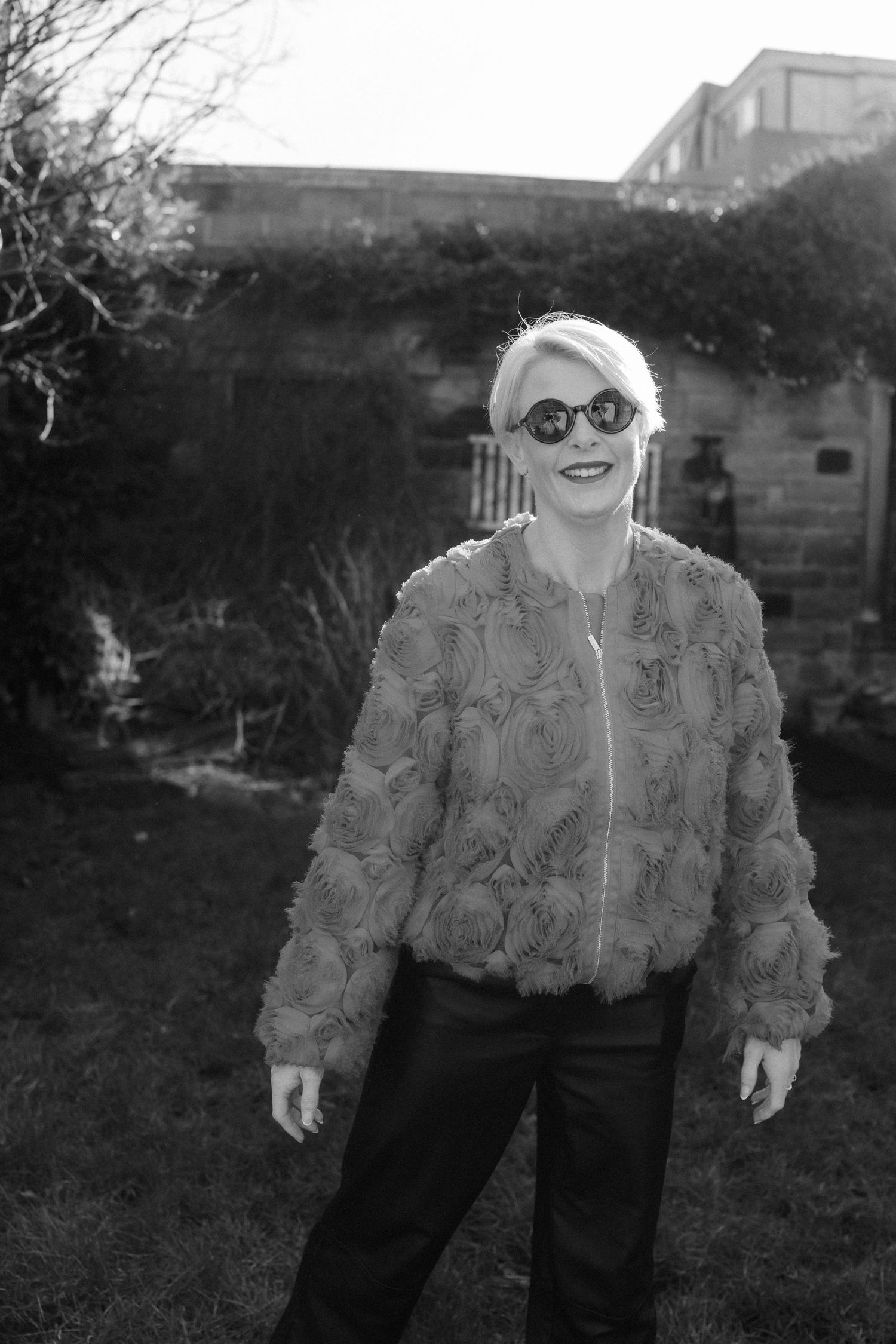 A person in a textured faux fur jacket and black pants poses outdoors in a series of casual stances.