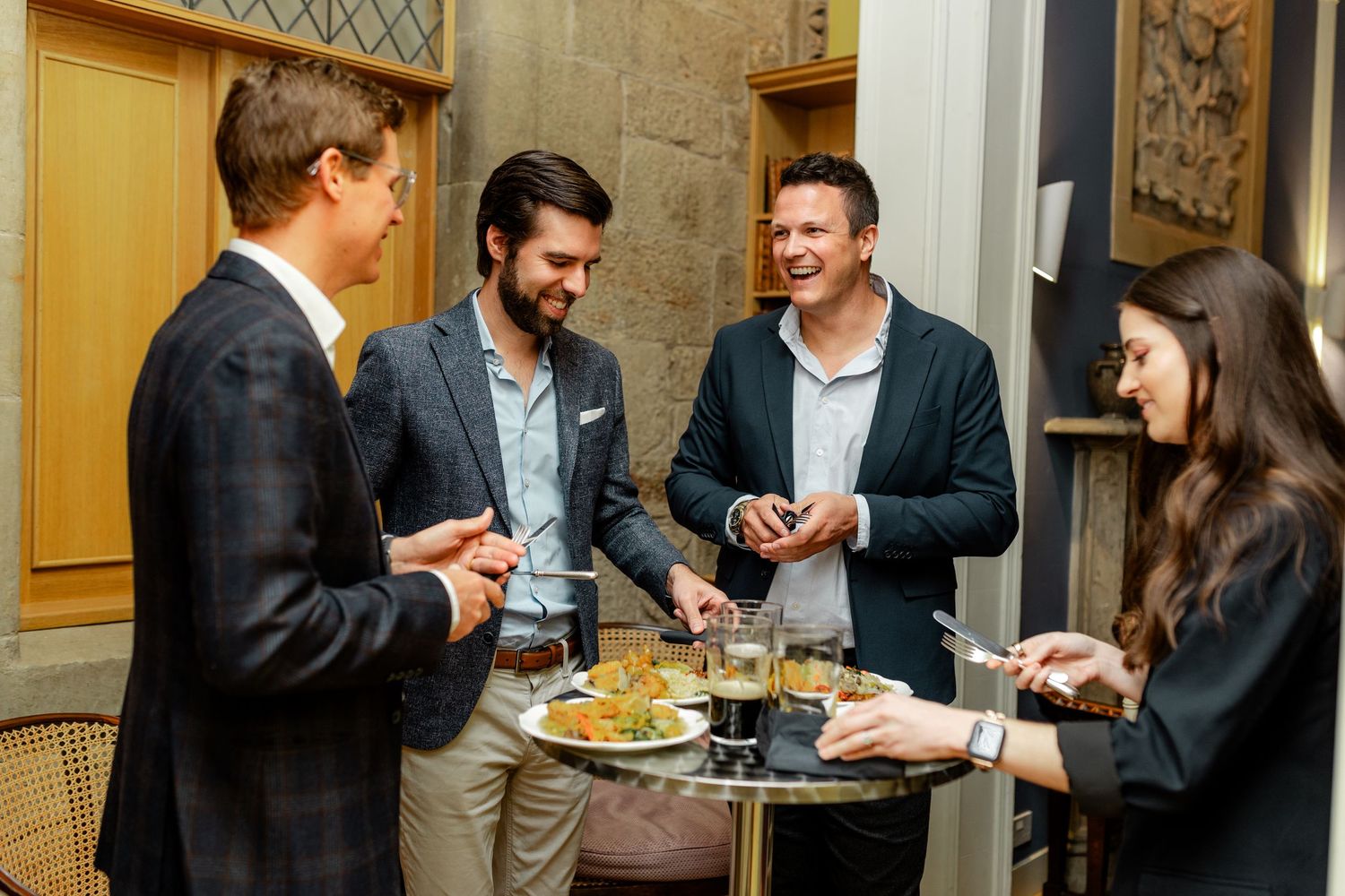 Well-dressed guests enjoying conversation and appetizers at an elegant indoor reception.