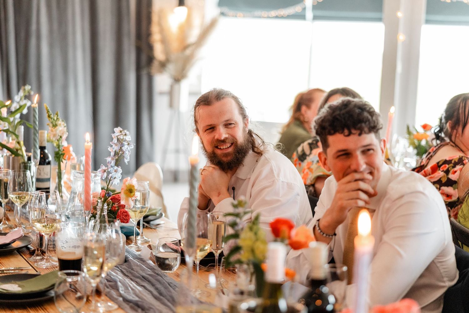 Guests seated at elegant wedding reception tables with floral arrangements and candlelight.