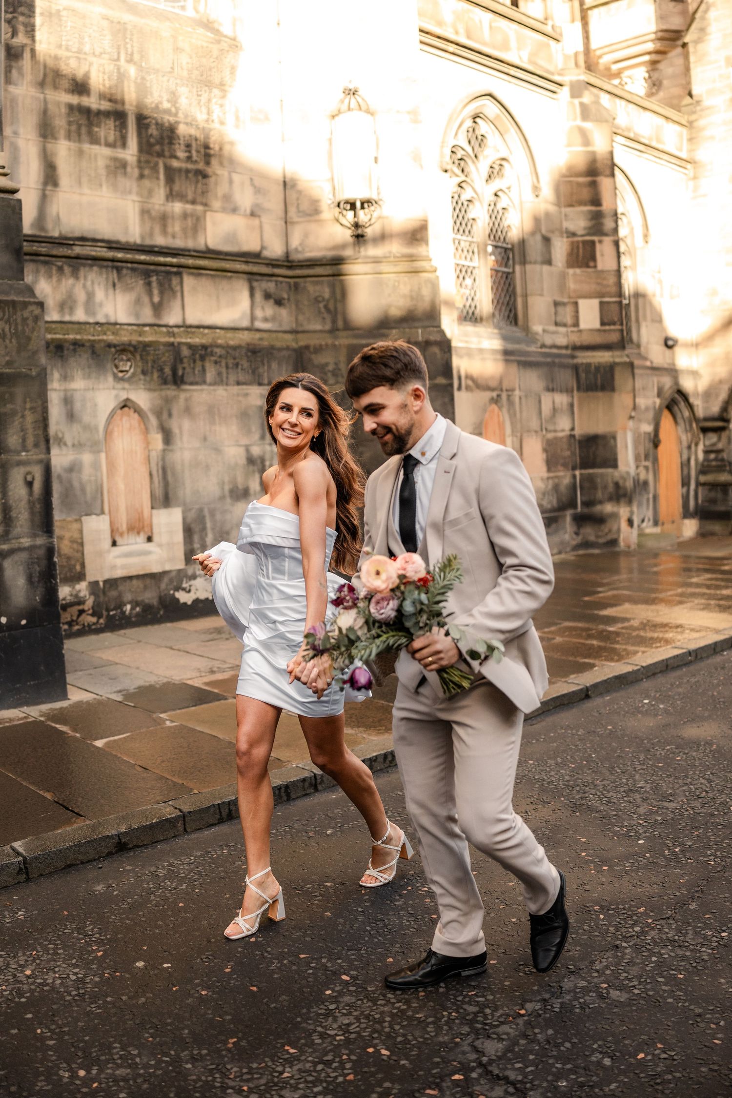 A couple dancing and twirling on cobblestones outside a historic building.
