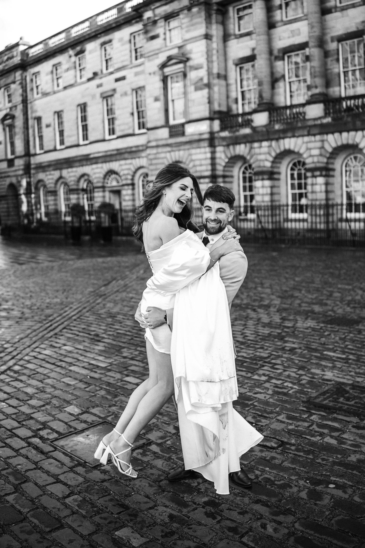 A romantic black and white photo shoot on cobblestone streets with historic architecture in the background.