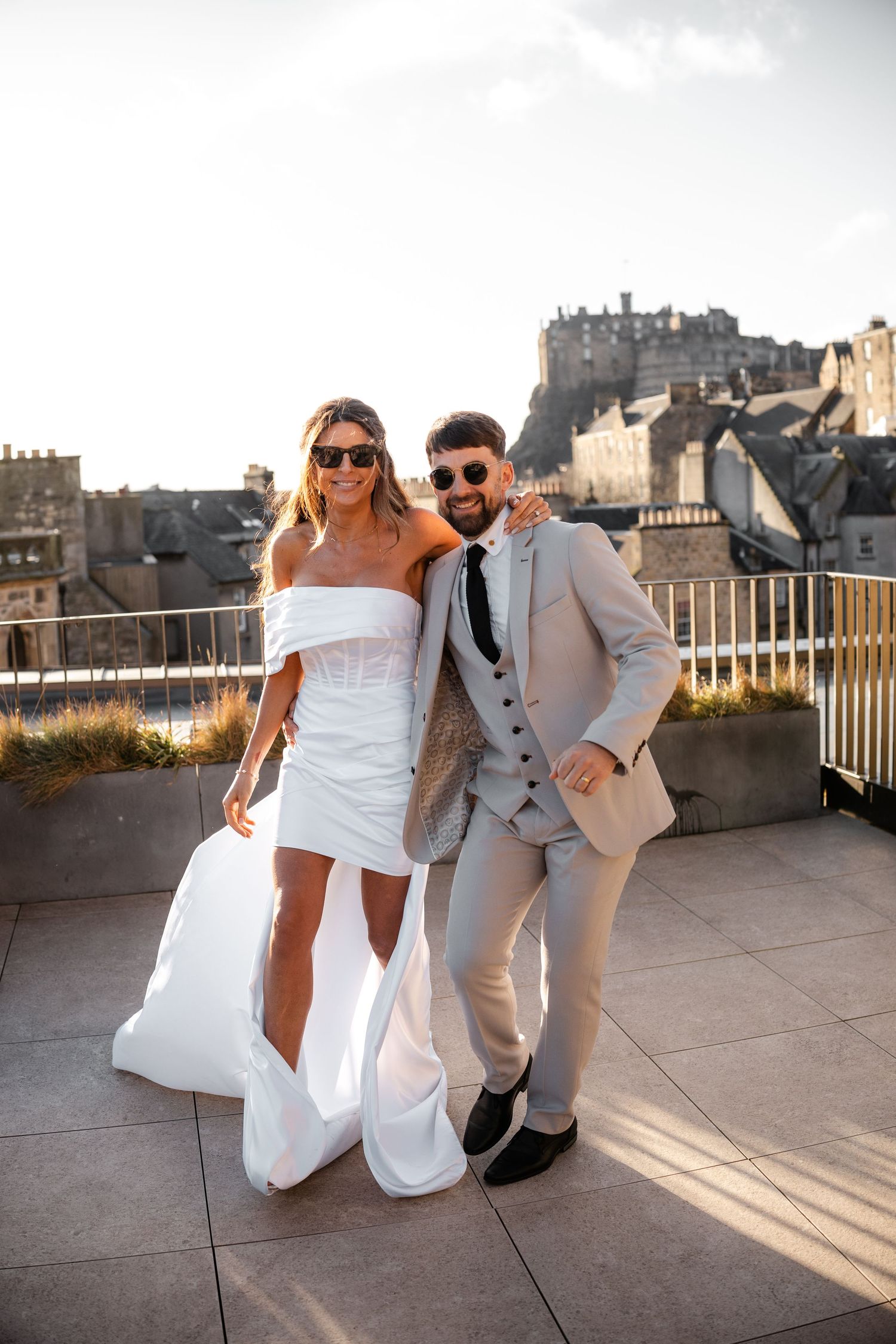 Wedding couple posing on a rooftop terrace with Edinburgh castle in the background.
