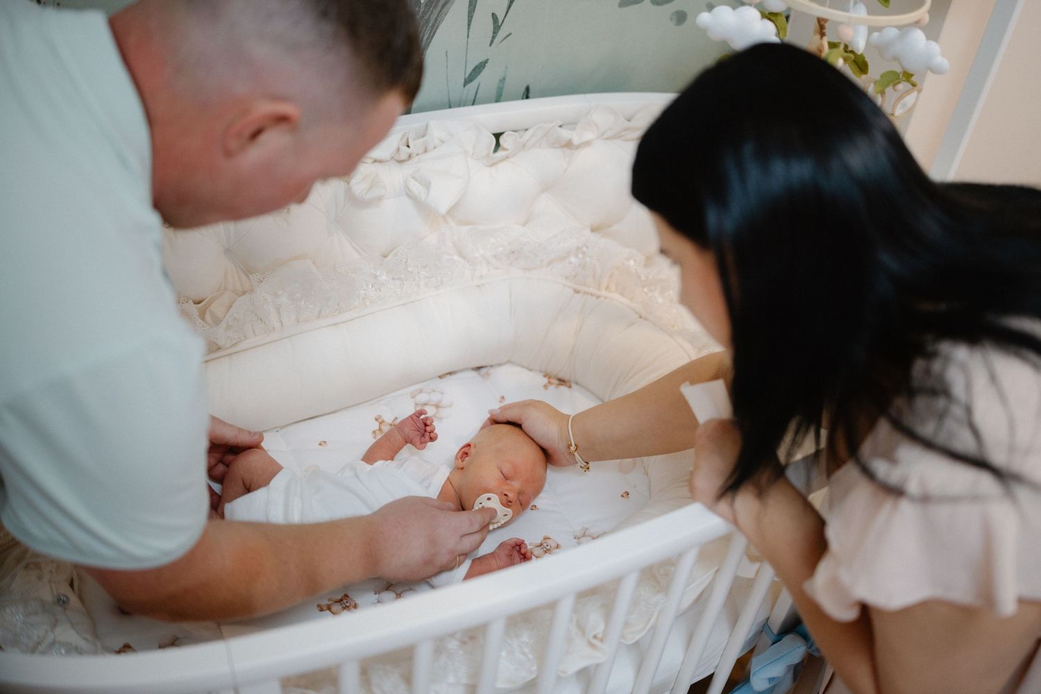 Group gathered around a white crib looking down at something special.
