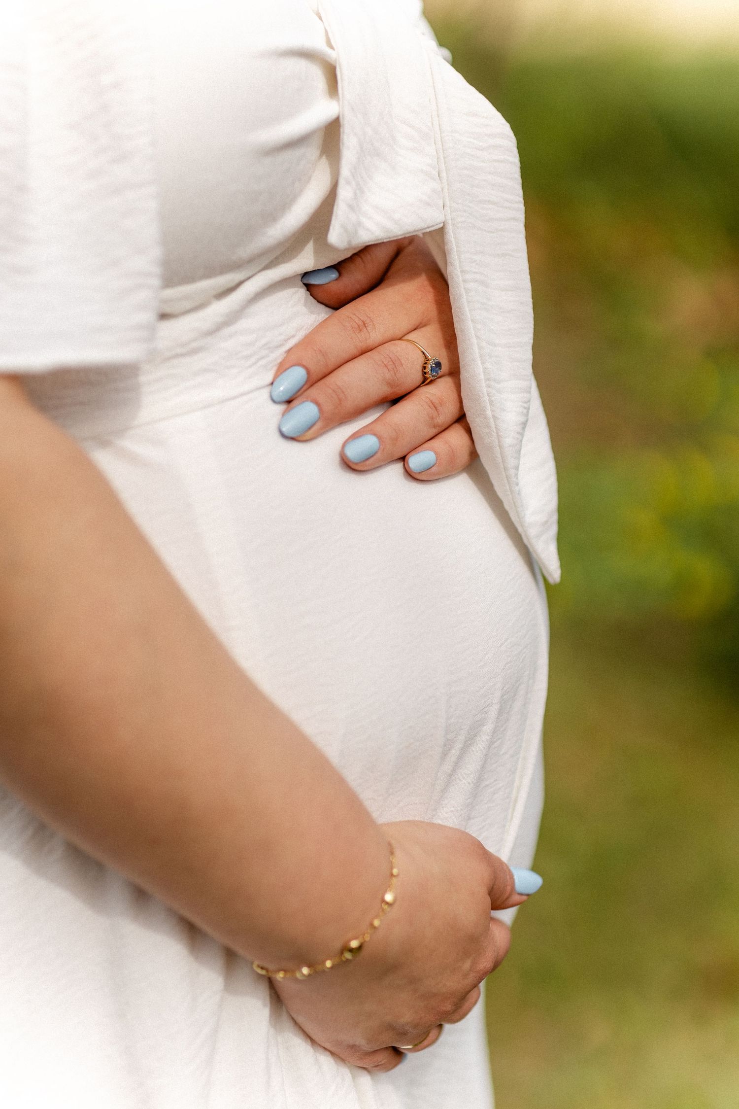 Close-up shots of hands gently cradling a pregnant belly with blue nail polish.