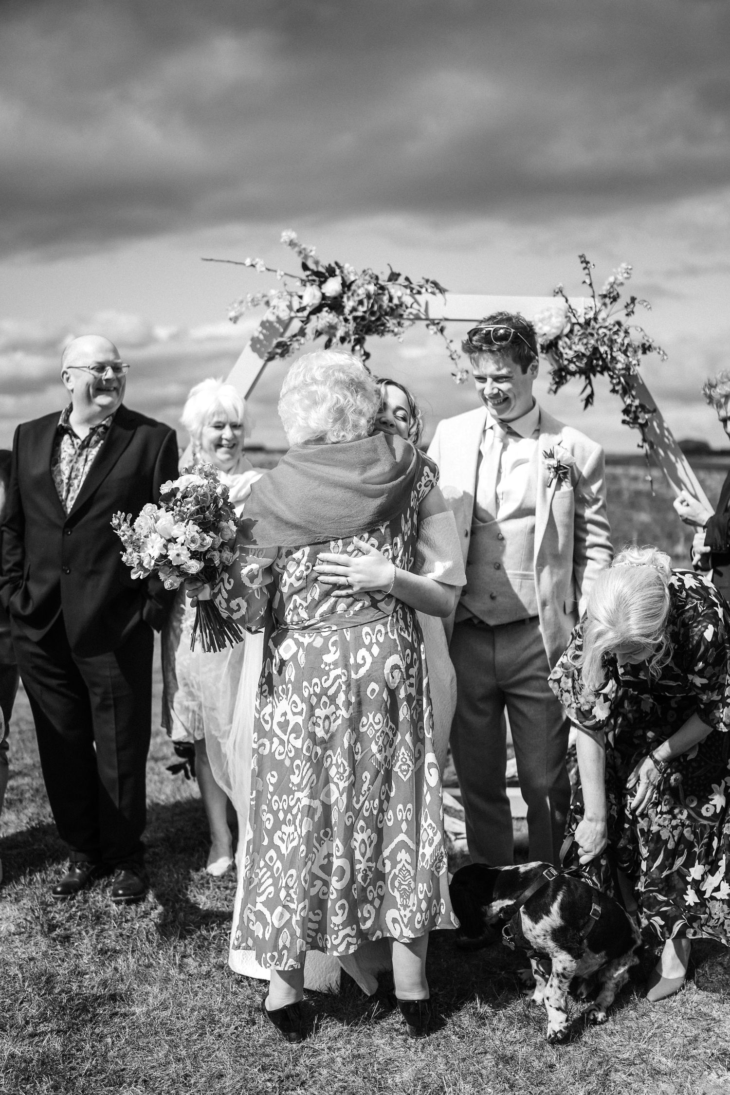 A group of elderly guests pose together outdoors in black and white photography.
