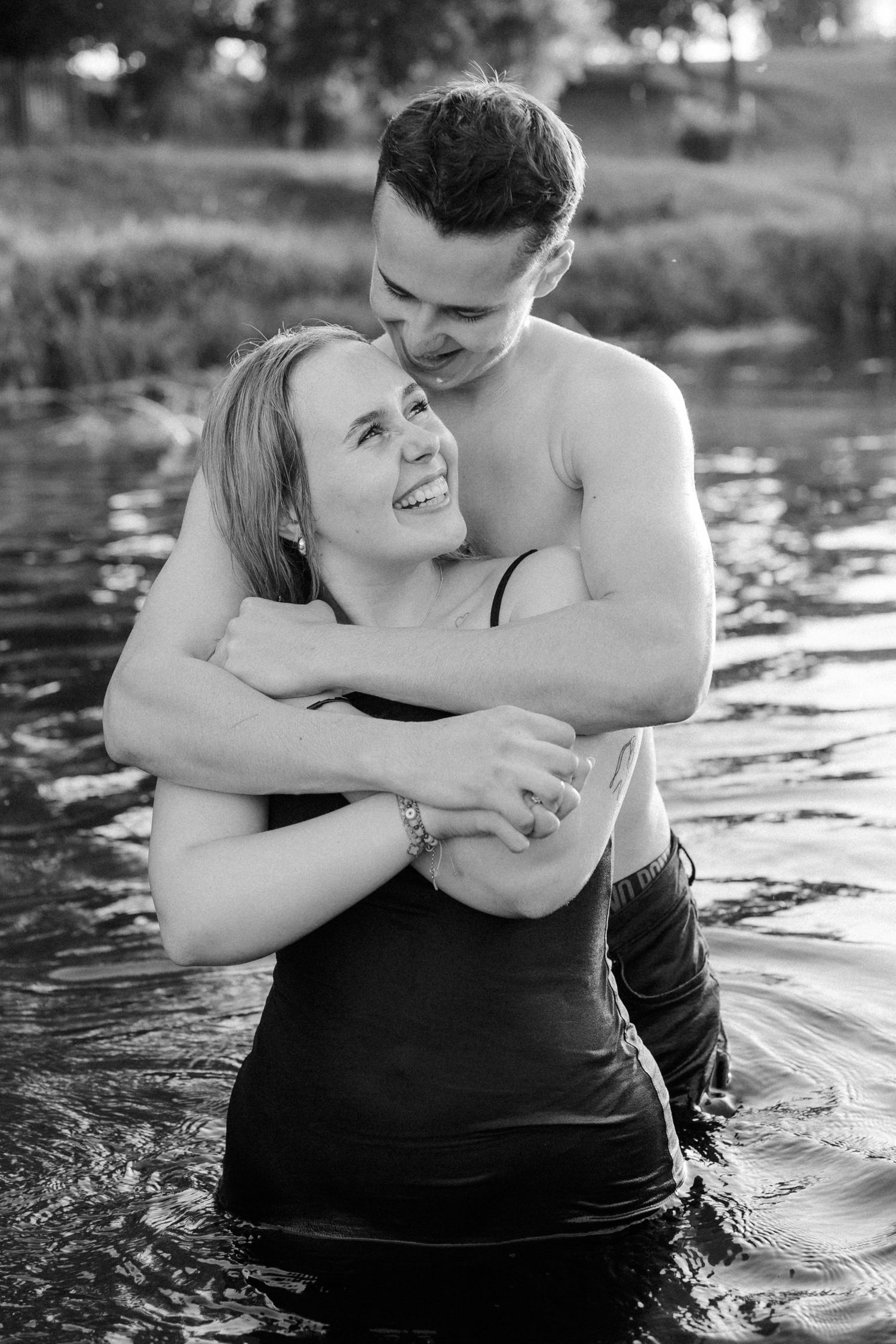 Couple embracing in lake water during romantic photoshoot.