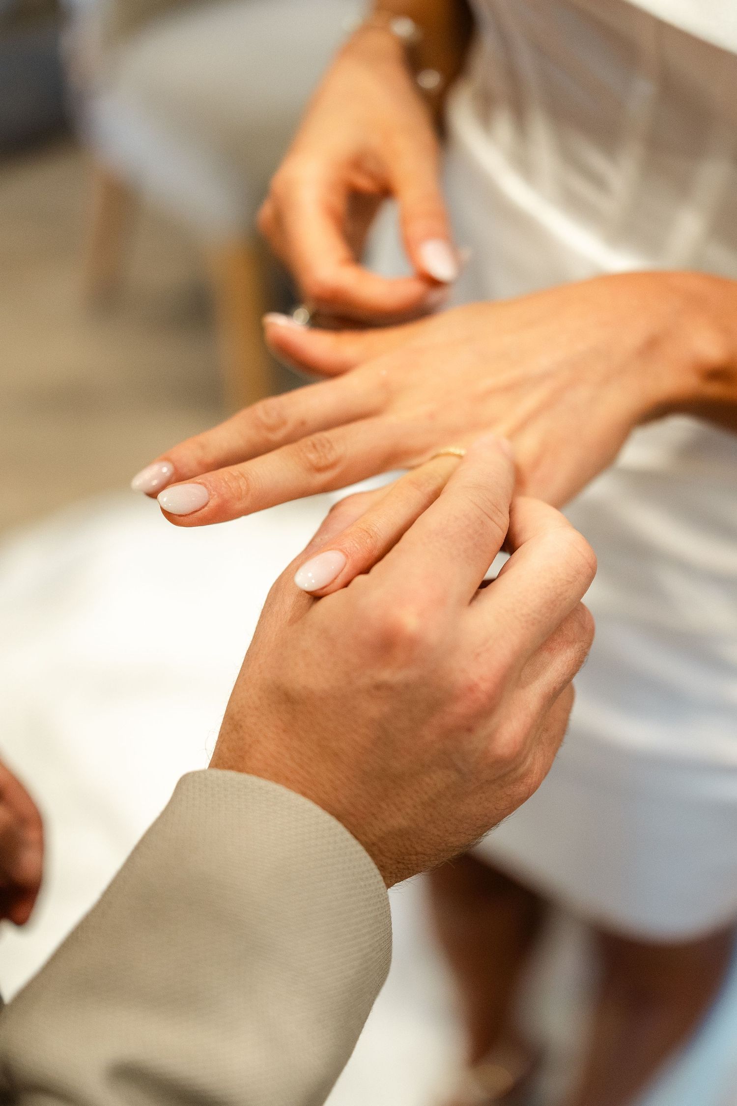 Hands exchanging rings during a wedding ceremony.