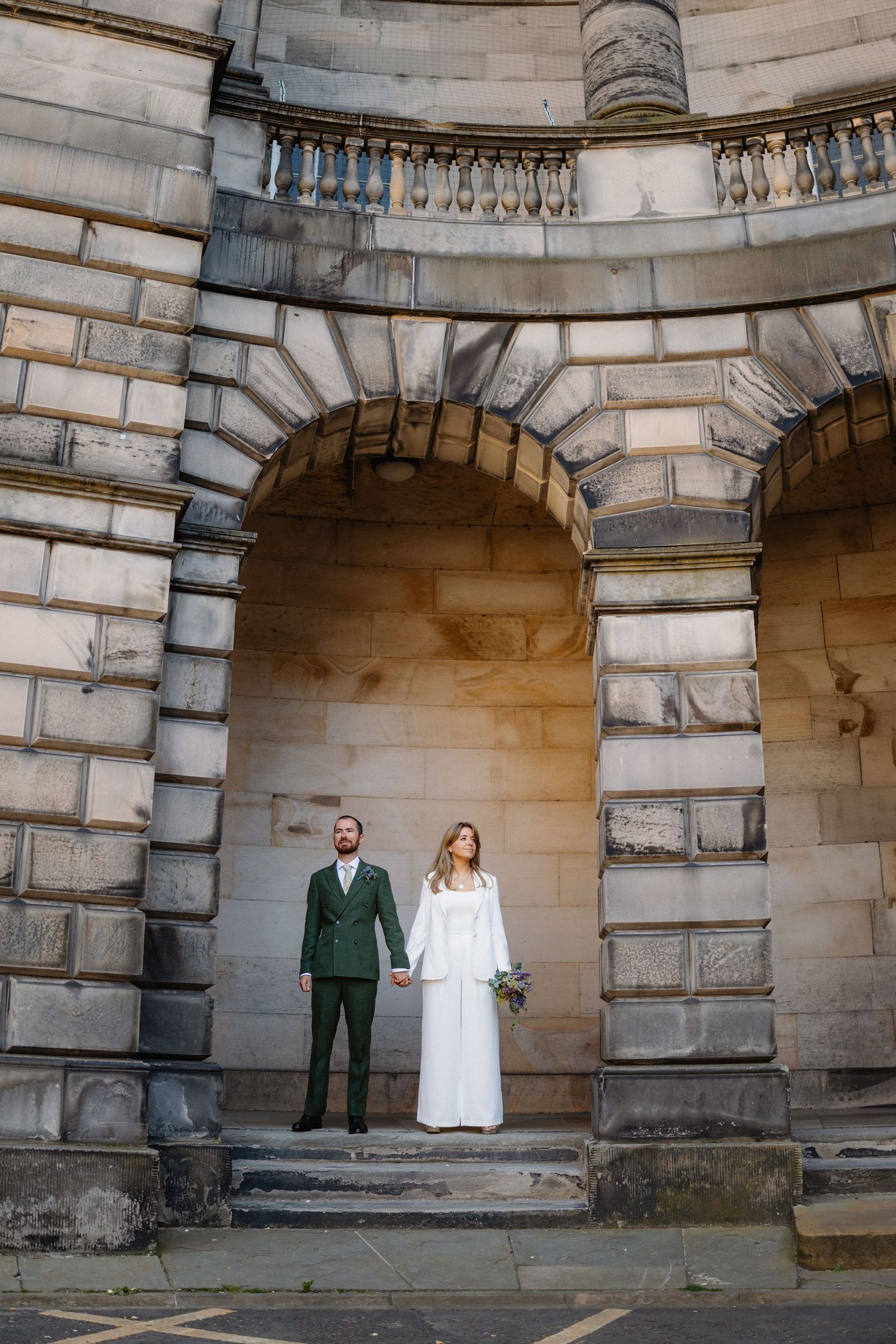 A couple standing in an ornate stone archway during a photo session.
