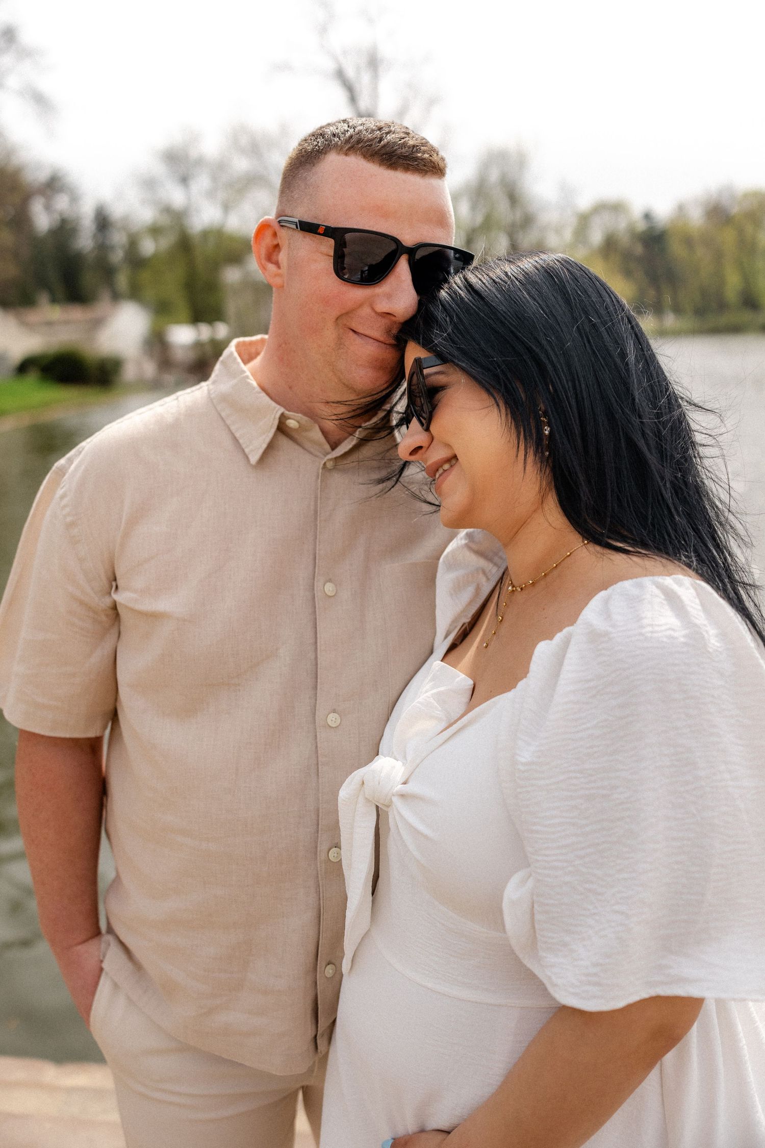 A couple shares tender moments together outdoors in matching white and beige outfits.