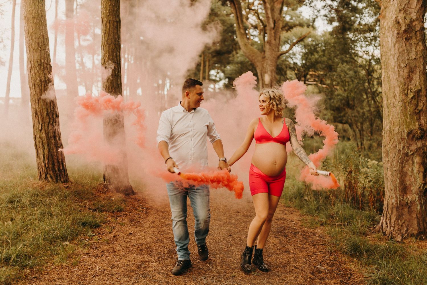 Couple walking through misty forest path with orange smoke effects.