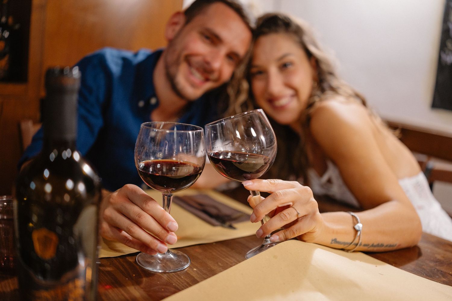 Couple enjoying wine and conversation at a cozy restaurant table.