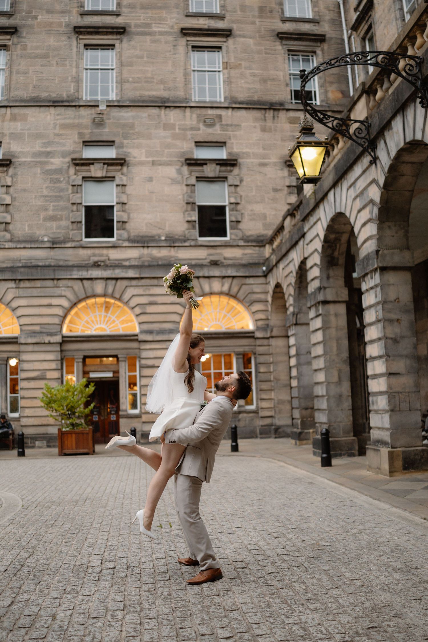A series of four dance movement photos captured in front of a historic stone building with arched windows and columns.