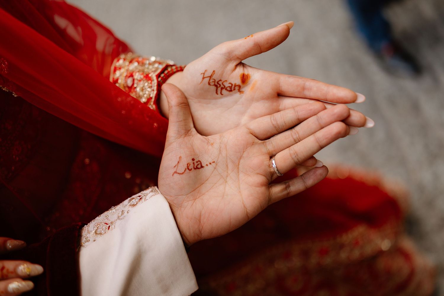 Close-up of bride's hands with intricate henna mehndi design and gold ring during Indian wedding ceremony.