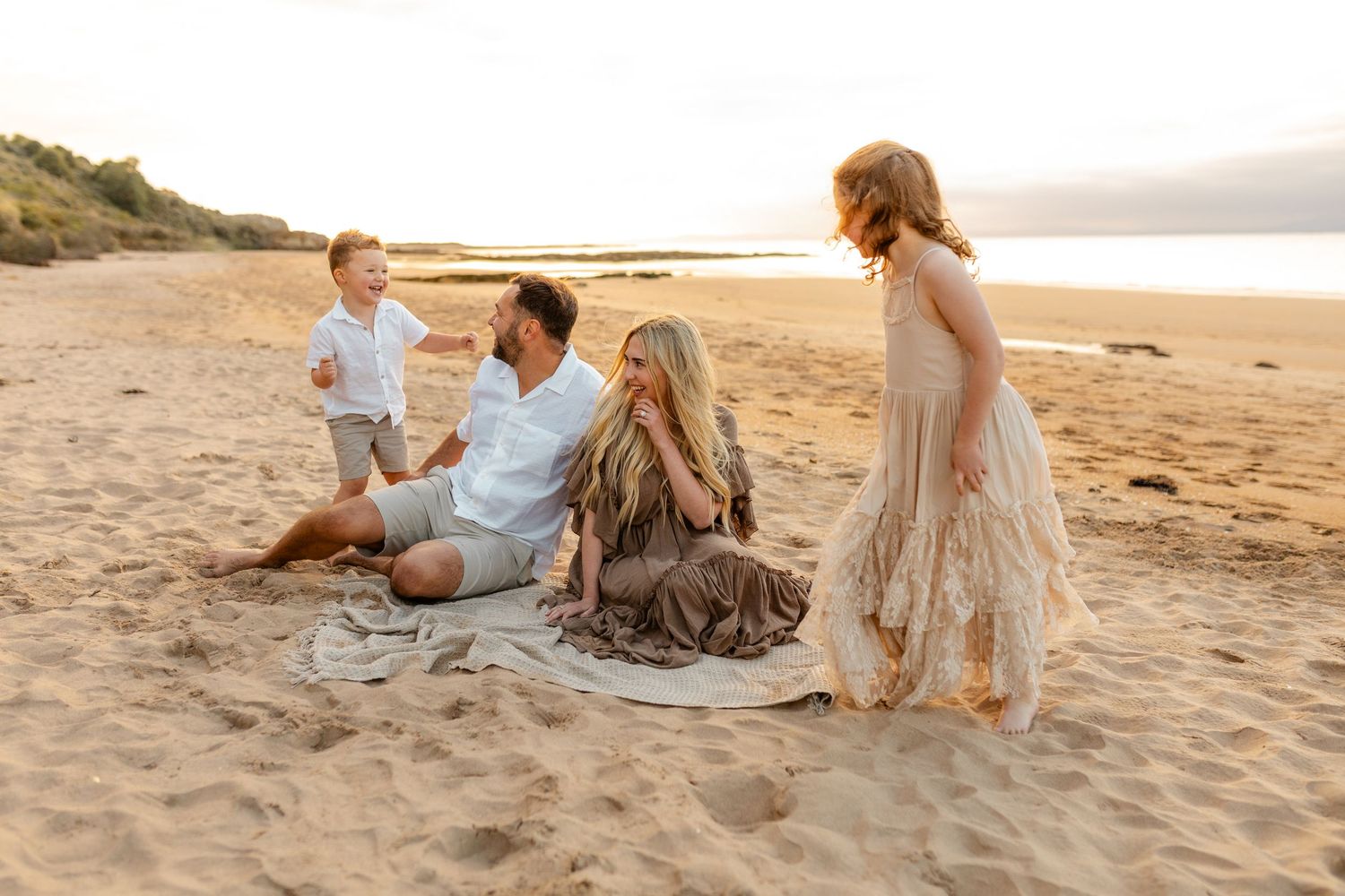 Romantic beach sequence at sunset with couple sitting on golden sand.