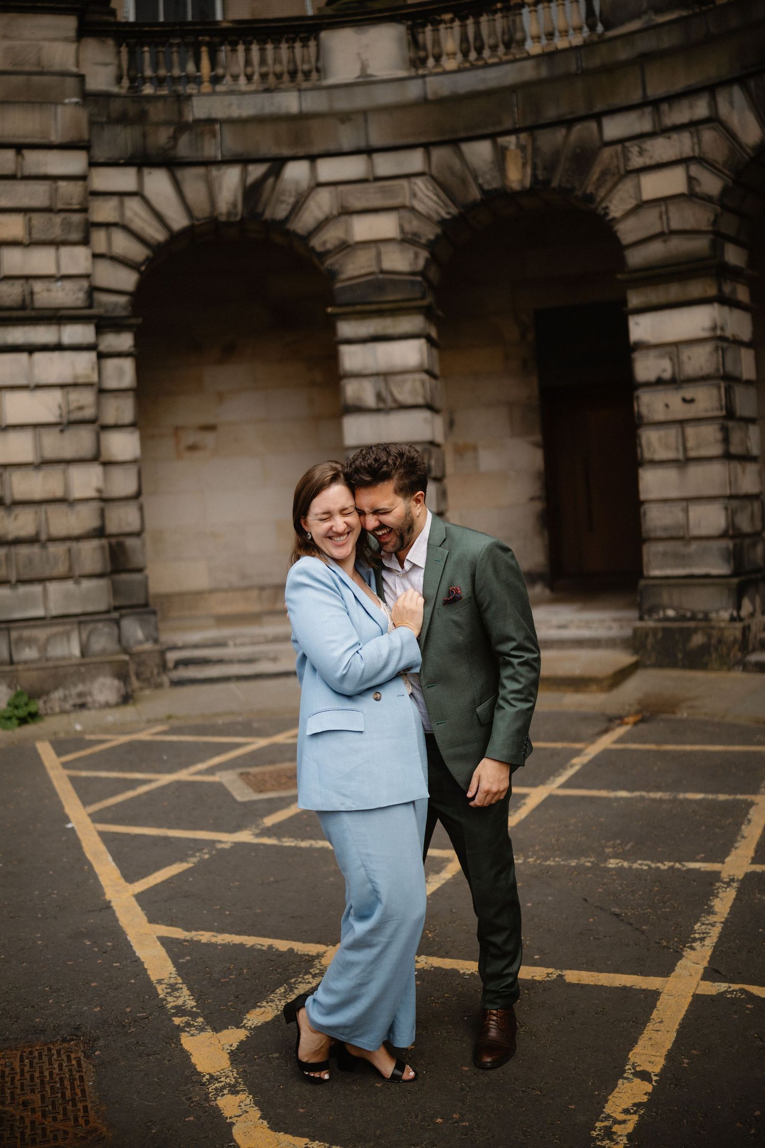 Couple sharing a tender moment against historic stone architecture.