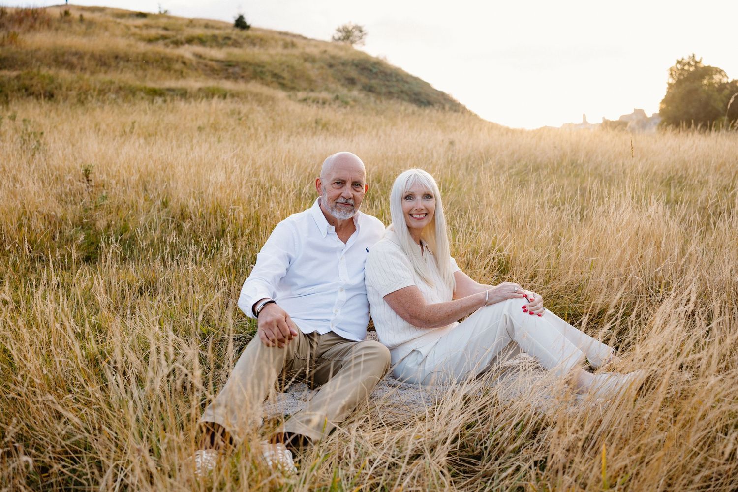 Family enjoying a playful moment together in a sunlit meadow during golden hour.