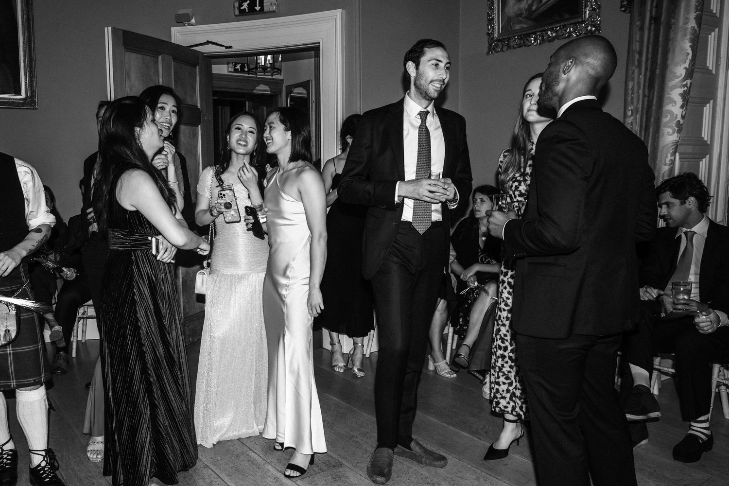 Wedding guests socializing at an elegant indoor reception with formal attire and drinks.