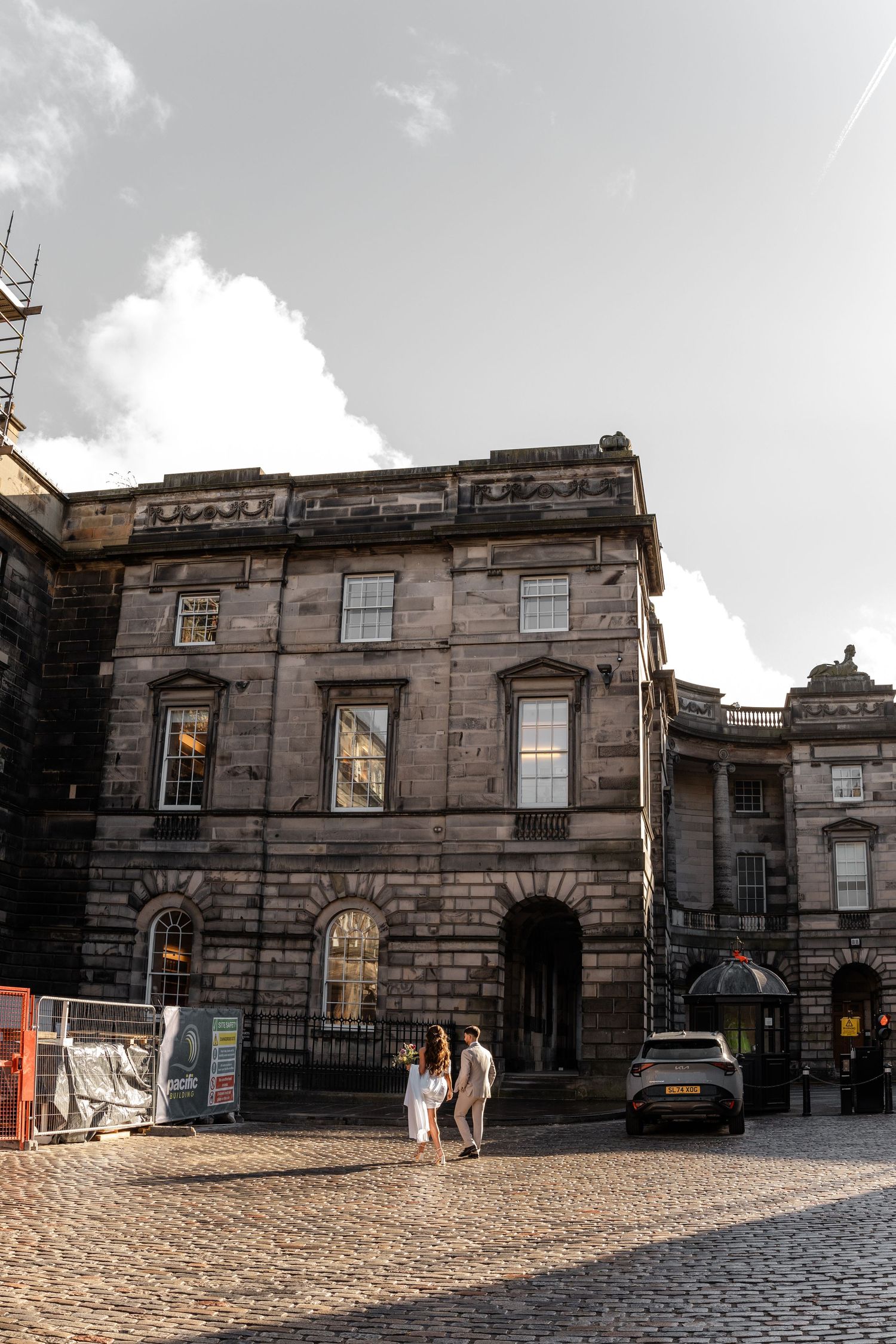 Historic stone building with arched windows and cobblestone street in Edinburgh.