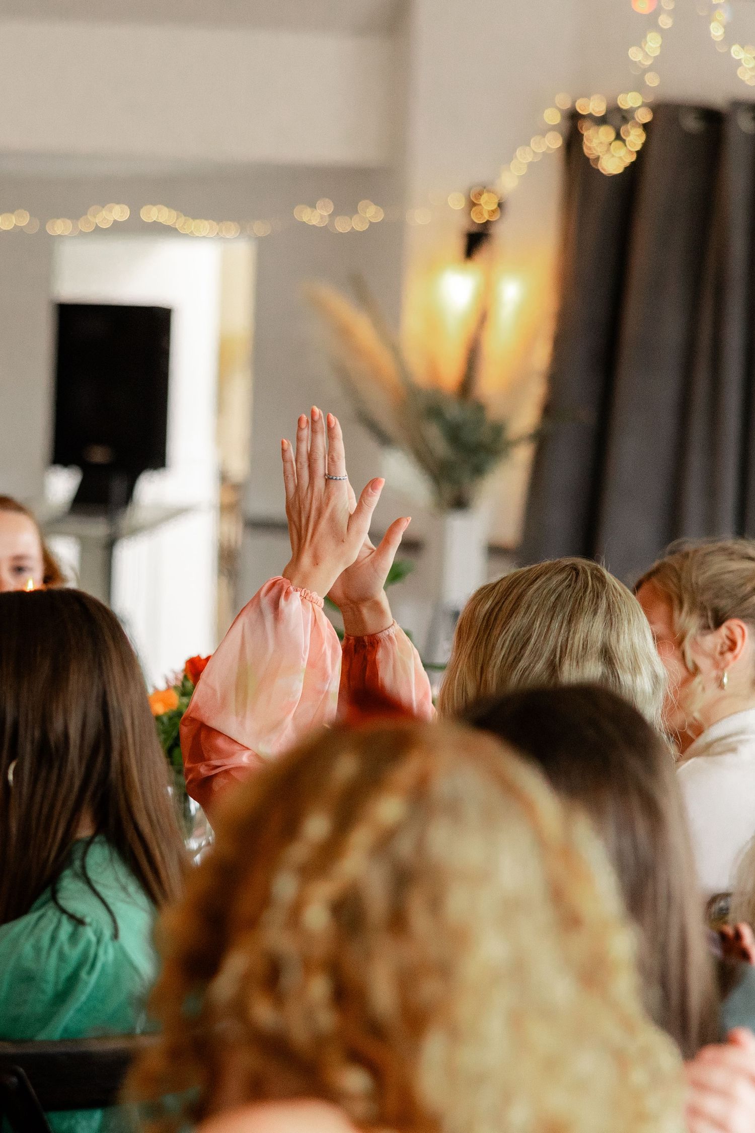 Wedding guests raising their hands during a celebratory moment at the reception.