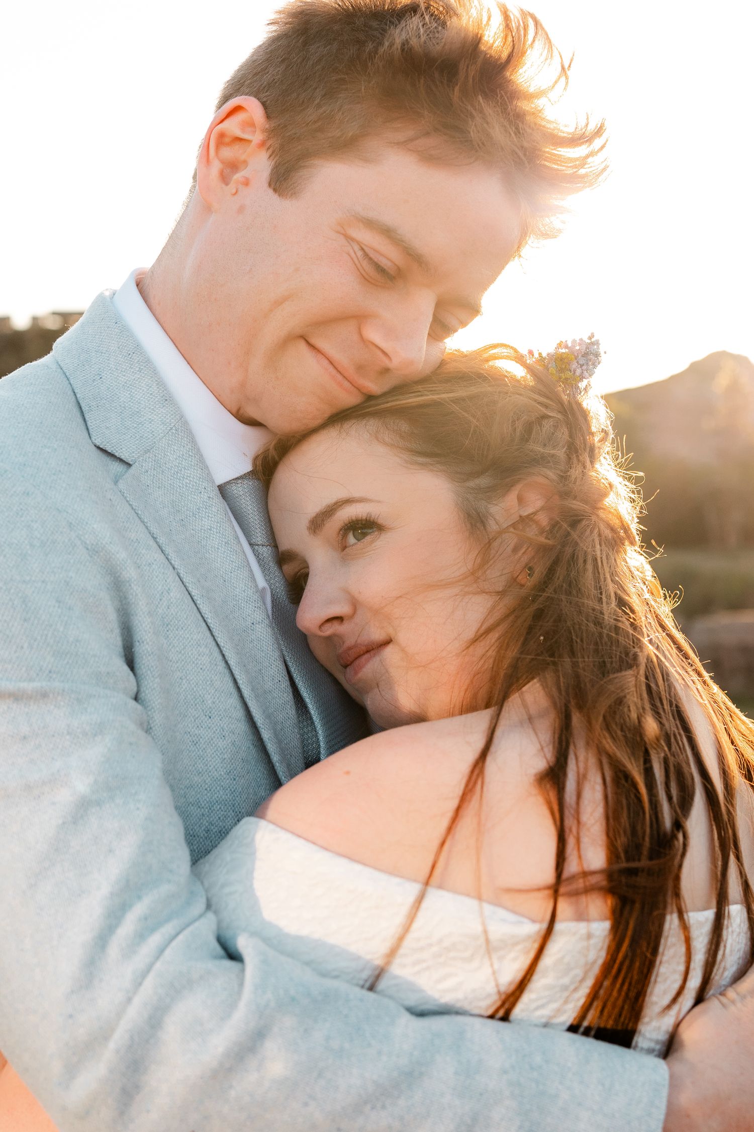 Romantic sunset portrait of a couple embracing in warm golden light.