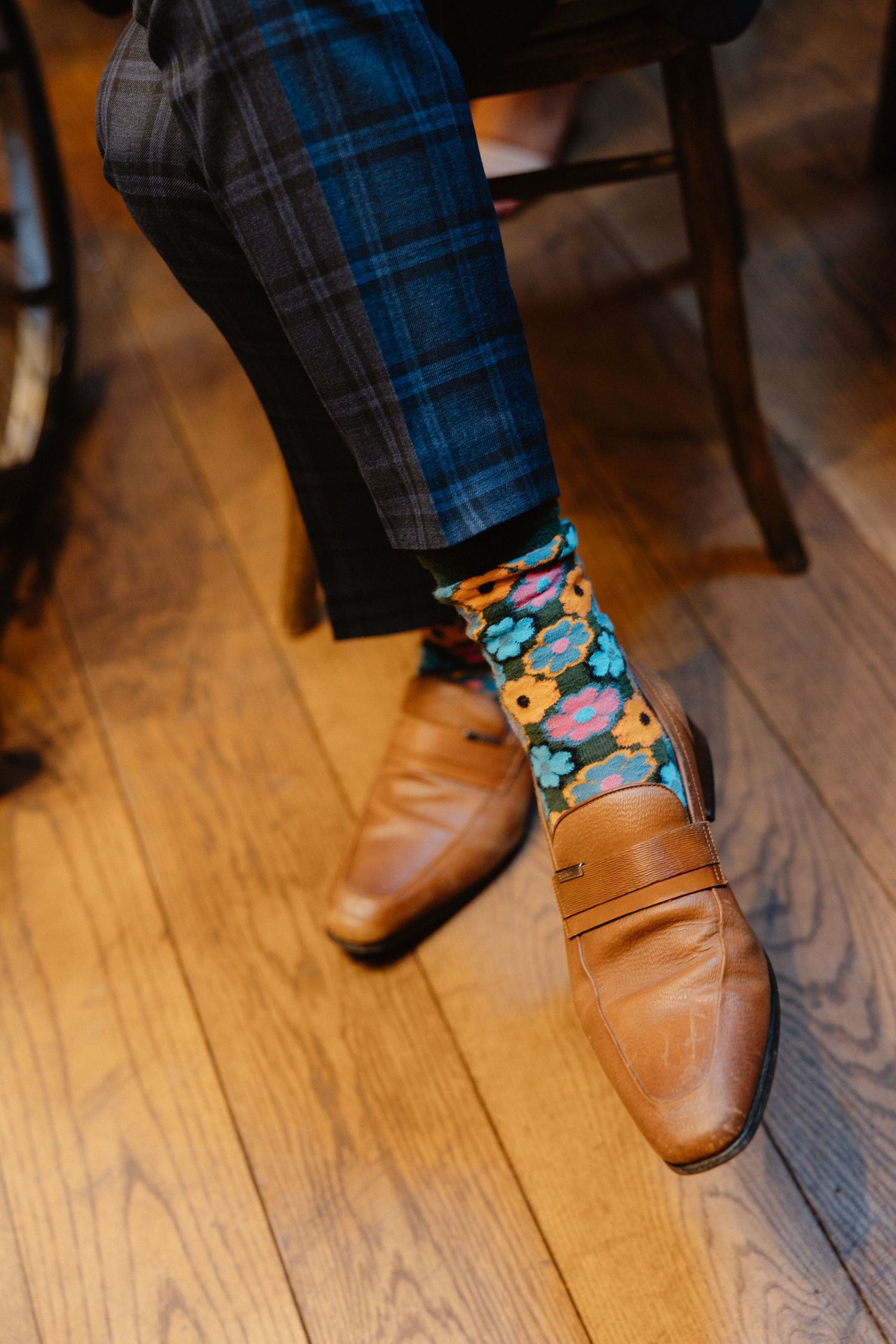 Fun patterned socks peeking out between brown leather shoes and plaid kilts.