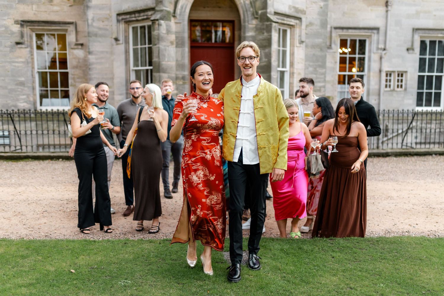 Guests mingling outside a historic stone building during a social gathering.