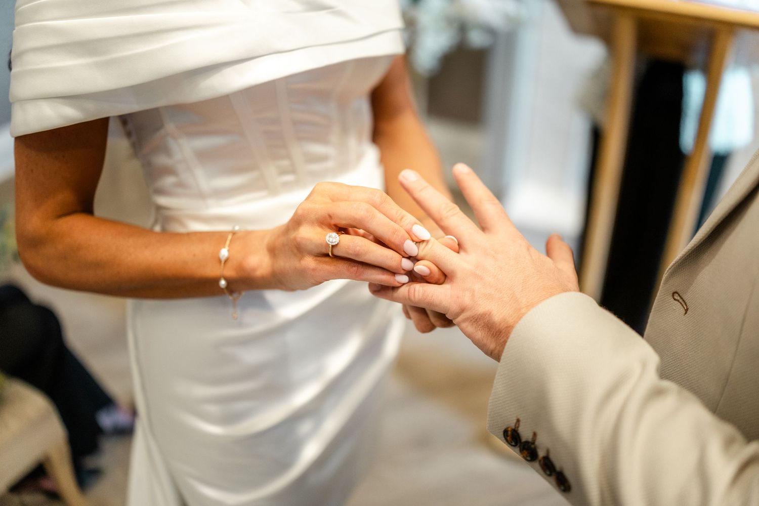 Close-up details of a wedding dress and hands during preparation.