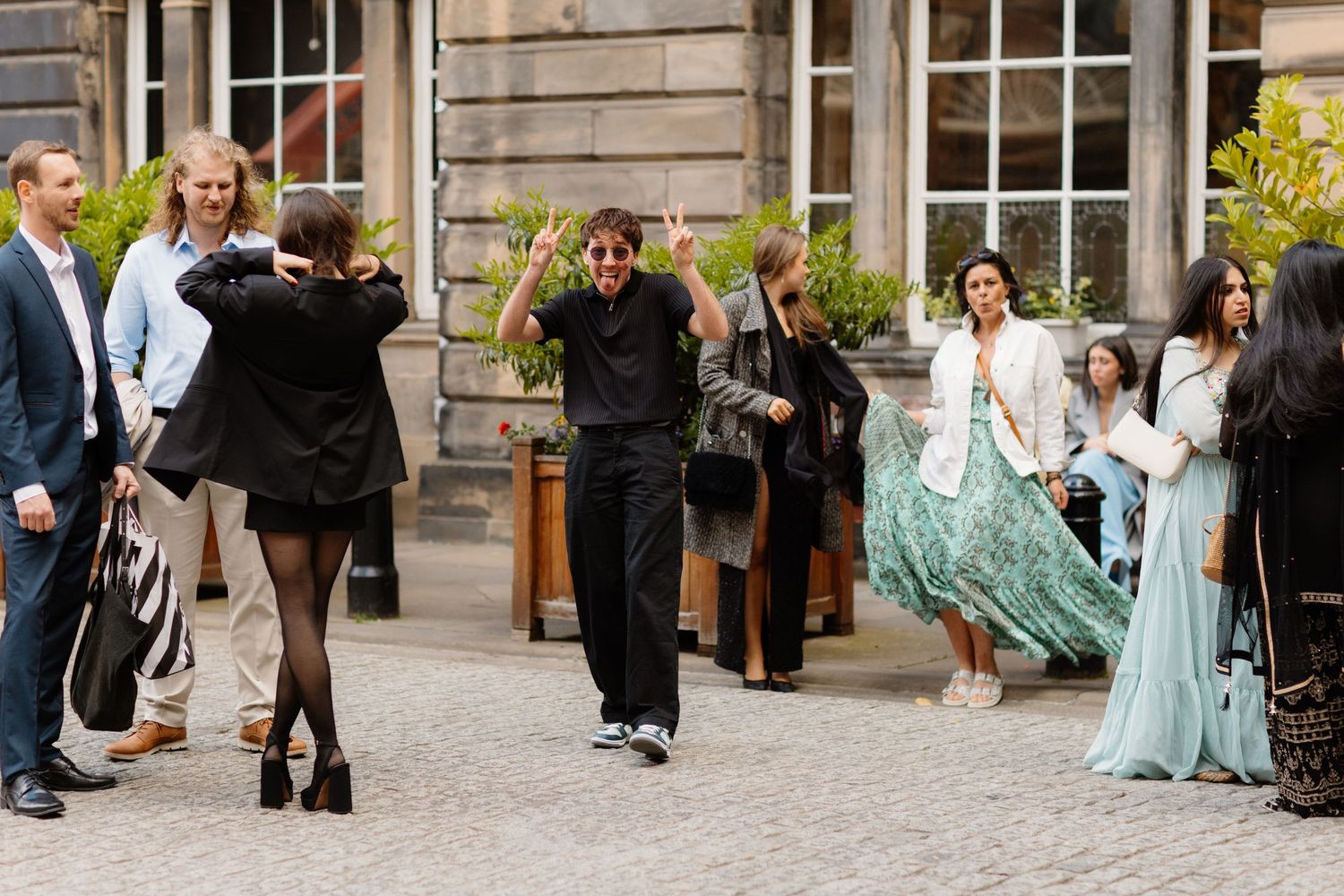 Wedding guests dancing and celebrating outdoors in a historic courtyard venue.