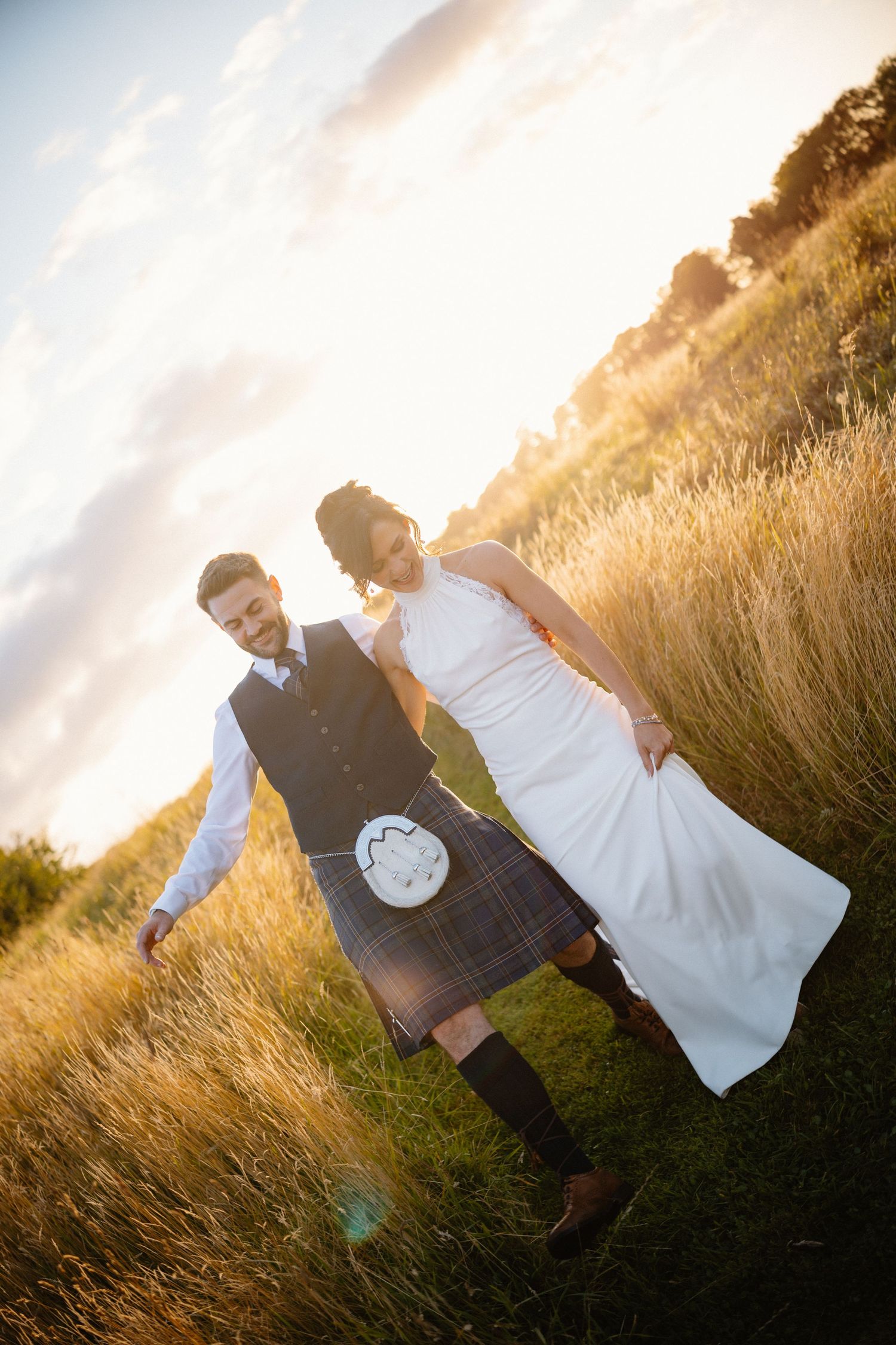 Couple walks through golden field during sunset wedding photoshoot.