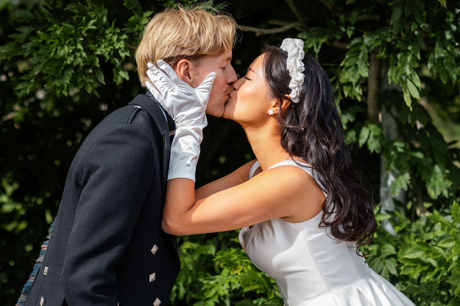 Romantic moment captured in lush garden setting during wedding celebration.