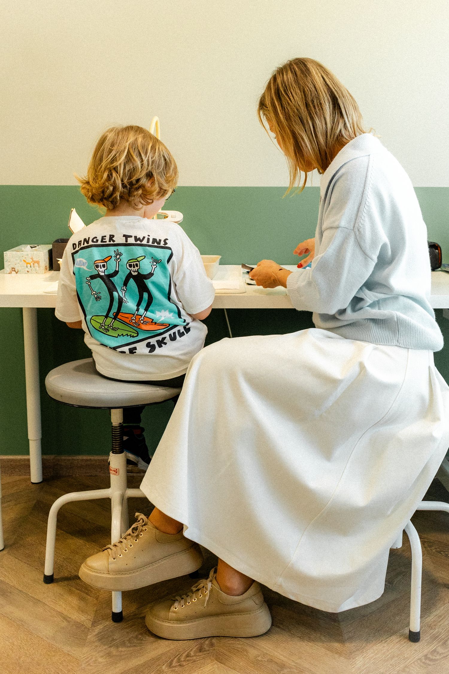 Person in white lab coat with illustrated design on back sitting at desk.